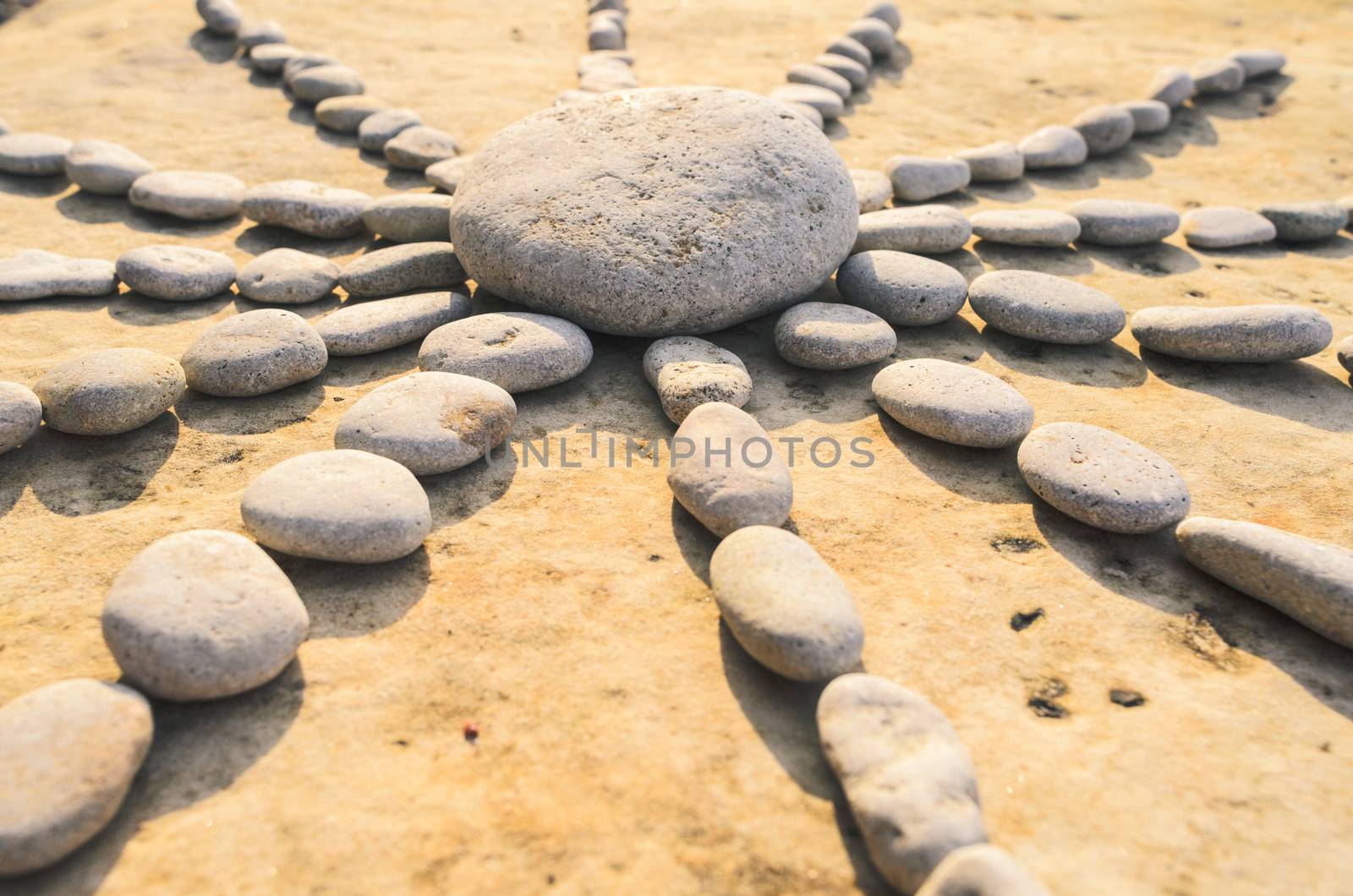 Symbol of sun made of stones on the surface boulder