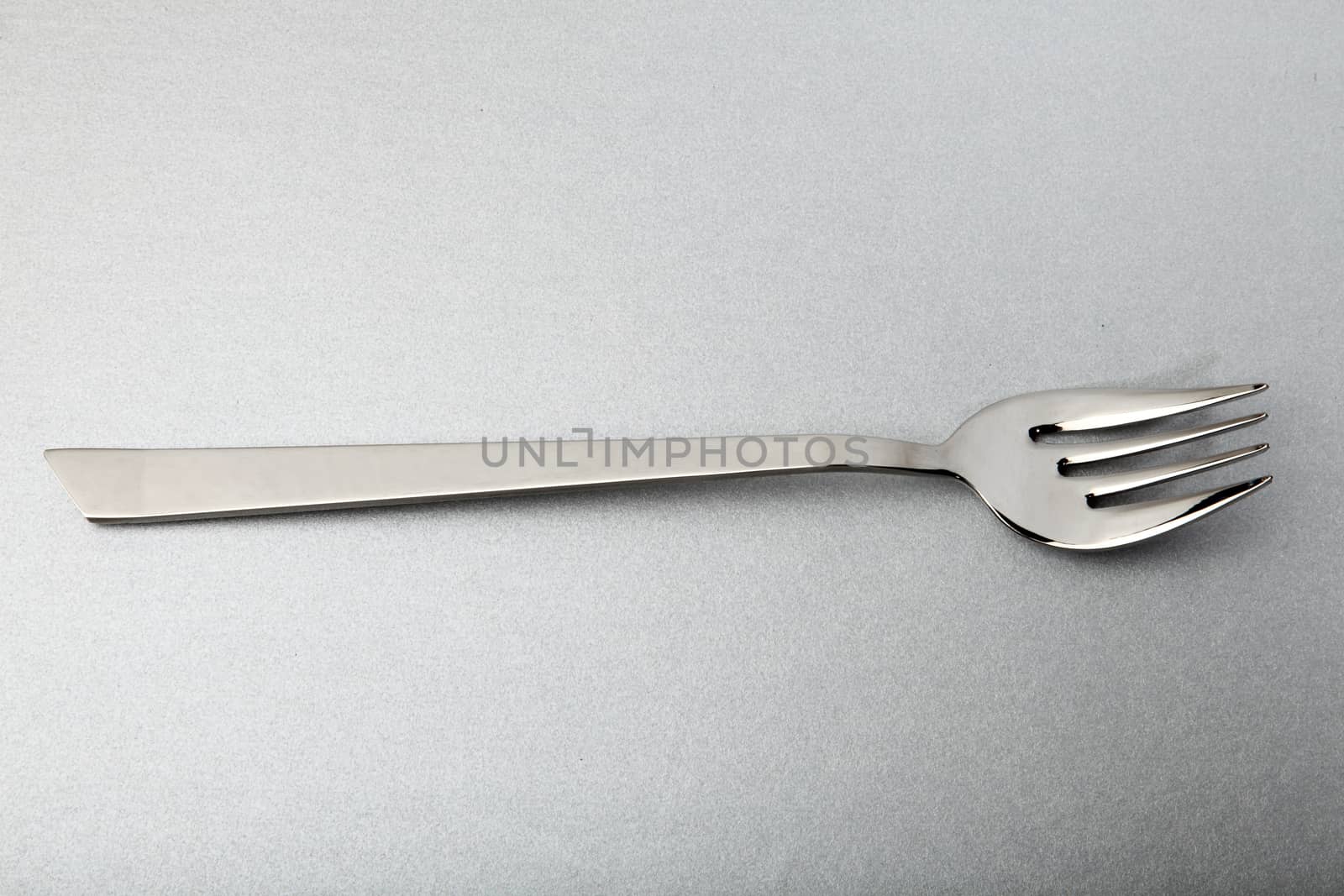 elegant steel fork for fish, on a silver background