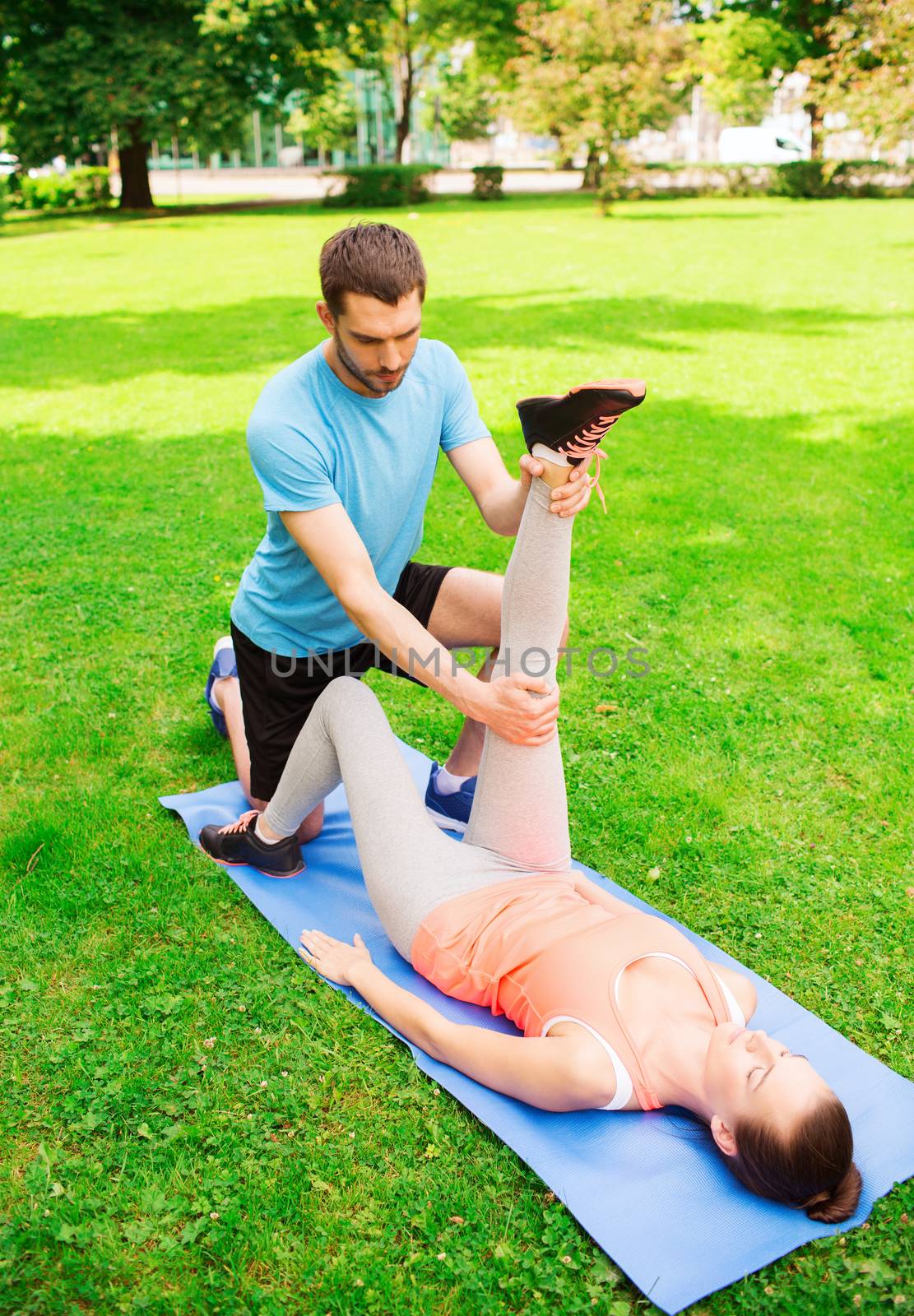 fitness, sport, training and lifestyle concept - serious couple stretching on mat outdoors