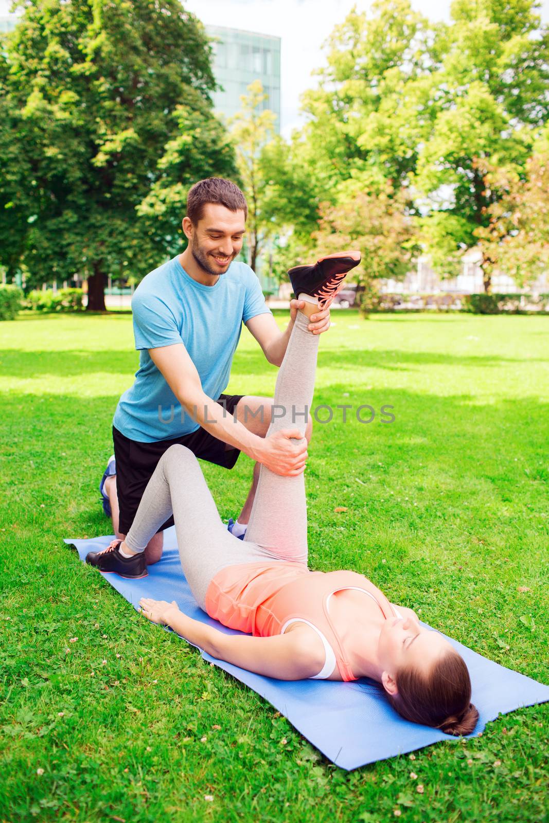 fitness, sport, training and lifestyle concept - smiling couple stretching on mat outdoors