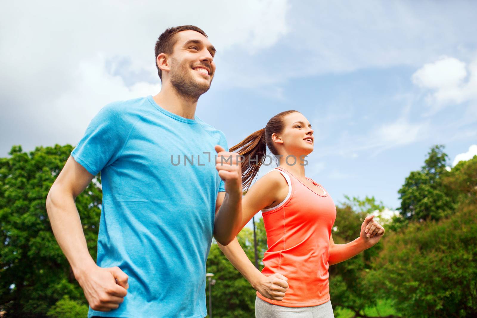 smiling couple running outdoors by dolgachov