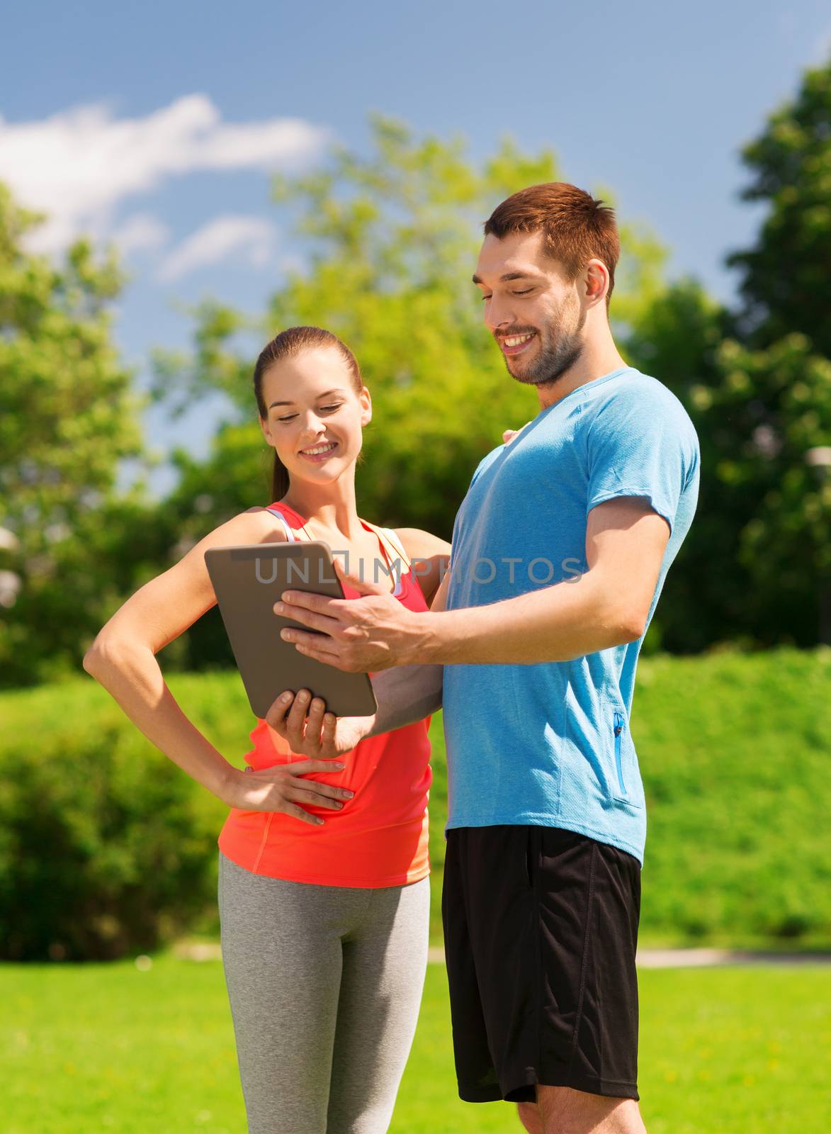 smiling couple with tablet pc outdoors by dolgachov