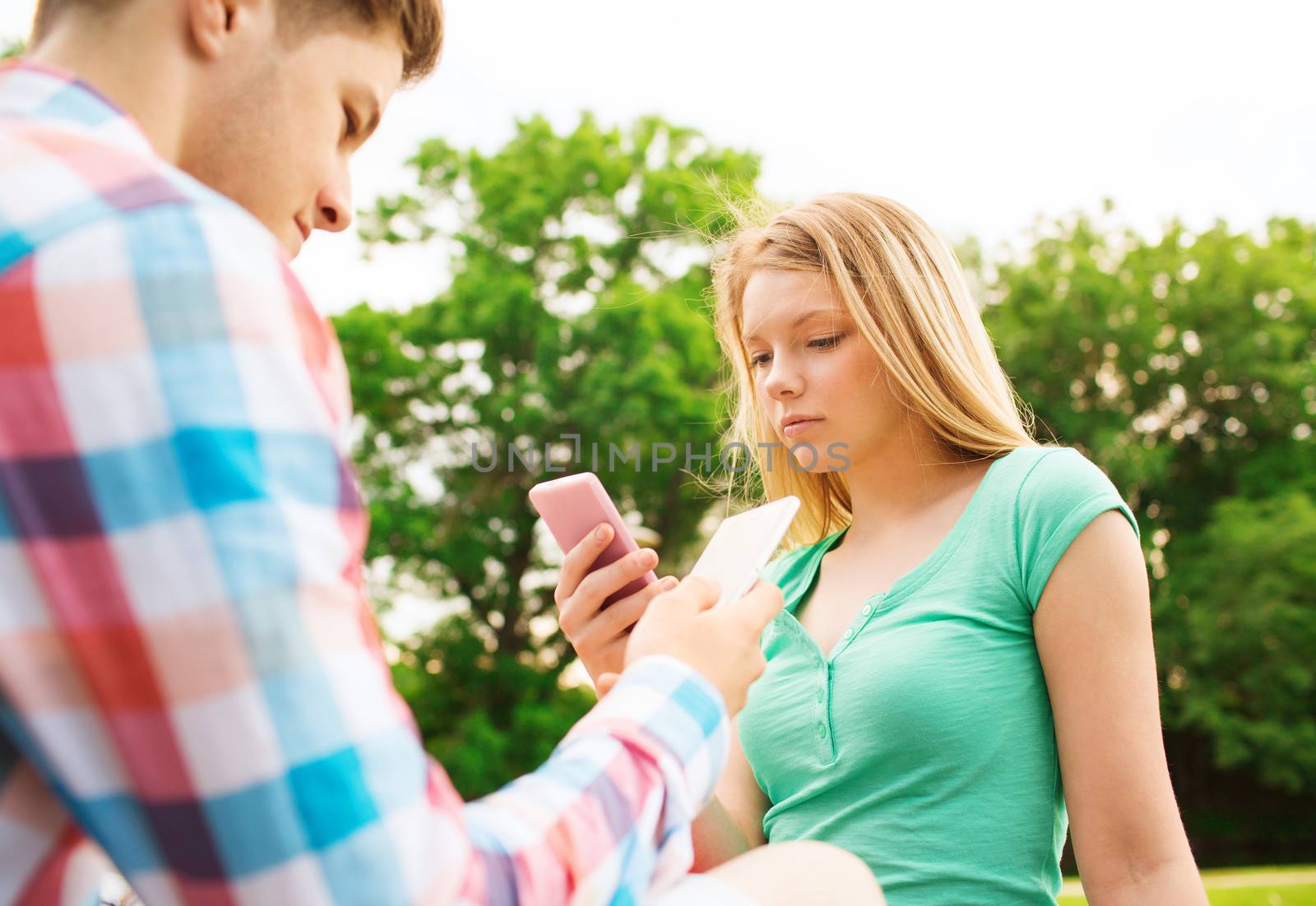 couple with smartphones in park by dolgachov