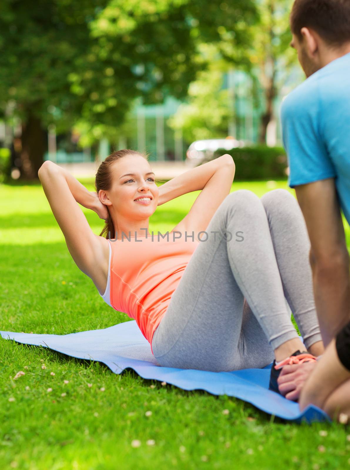 fitness, sport, training, park and lifestyle concept - smiling woman with personal trainer doing exercises on mat outdoors