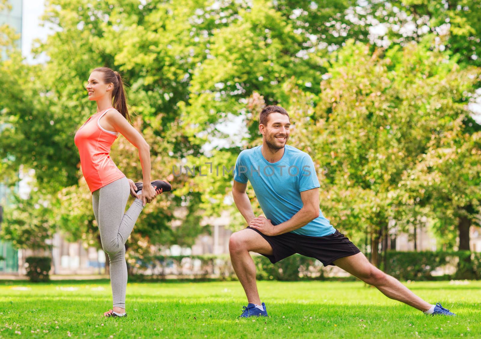 fitness, sport, training and lifestyle concept - smiling couple stretching outdoors