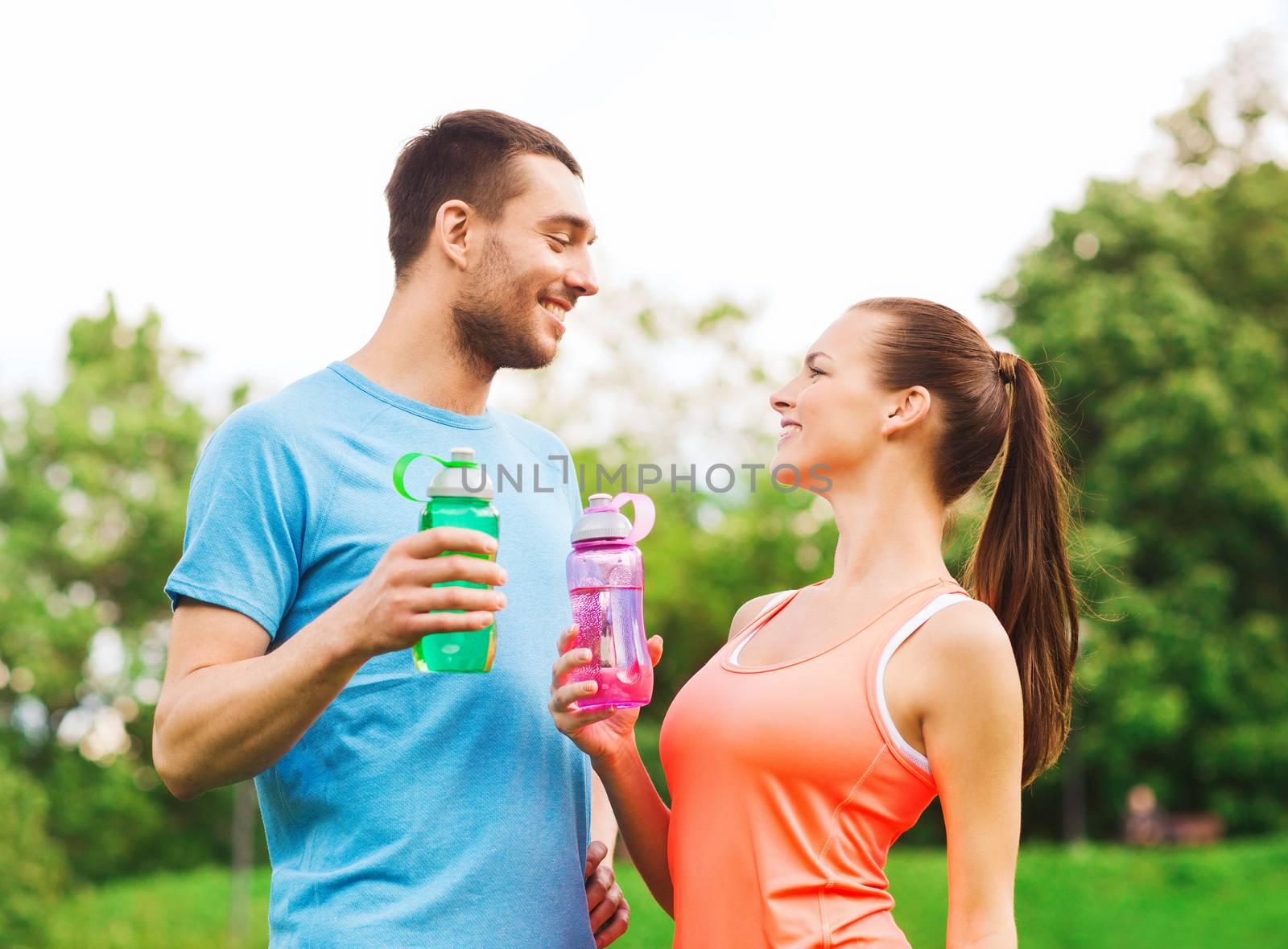 smiling couple with bottles of water outdoors by dolgachov