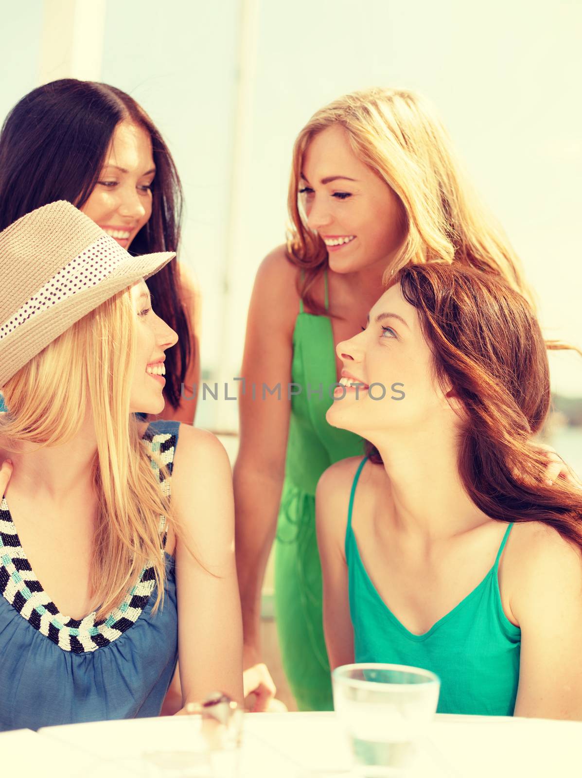 group of smiling girls in cafe on the beach by dolgachov