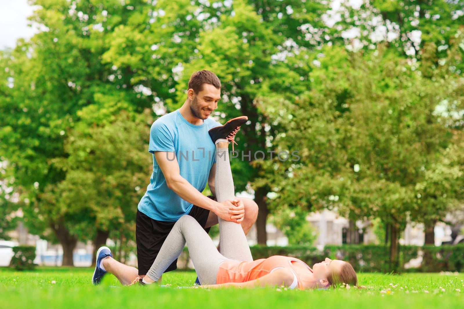 fitness, sport, training and lifestyle concept - smiling couple stretching outdoors