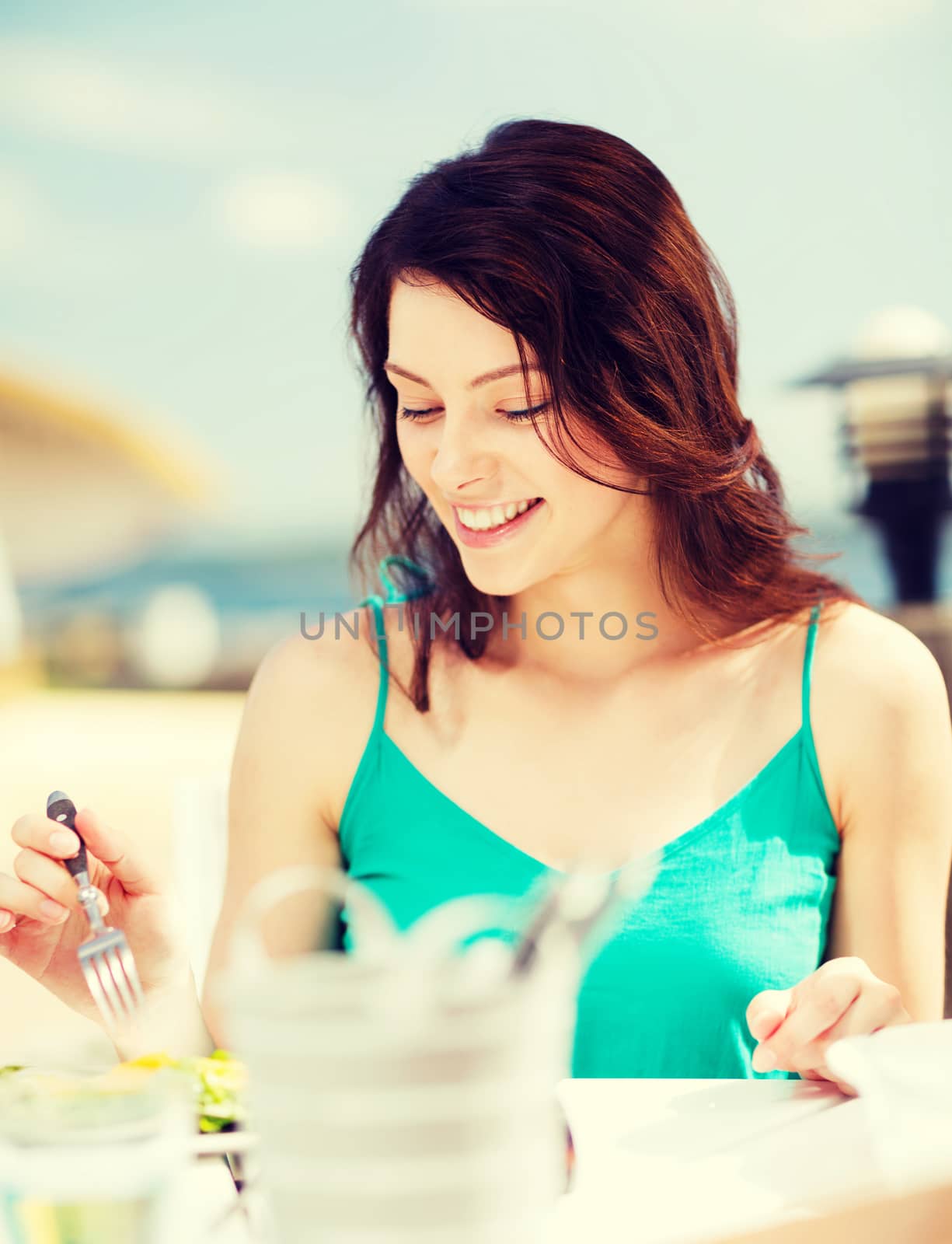 summer holidays and vacation - girl eating in cafe on the beach