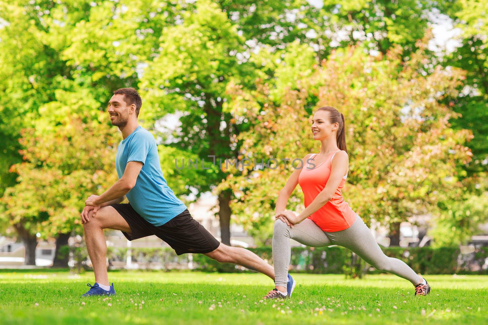 fitness, sport, training and lifestyle concept - smiling couple stretching outdoors