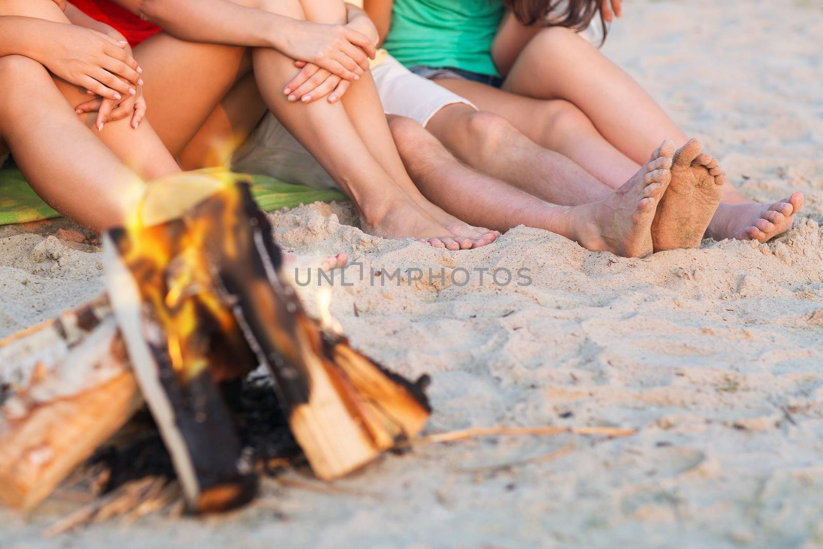 close up of friends sitting on summer beach by dolgachov