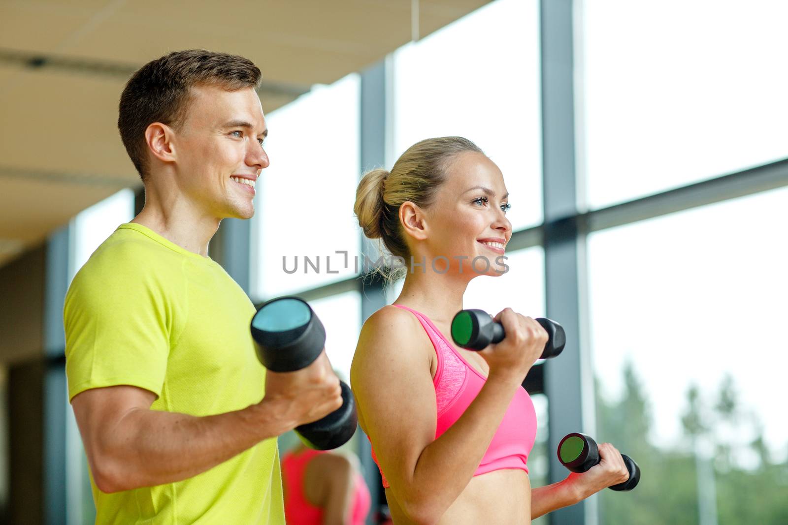 sport, fitness, lifestyle and people concept - smiling man and woman with dumbbells exercising in gym