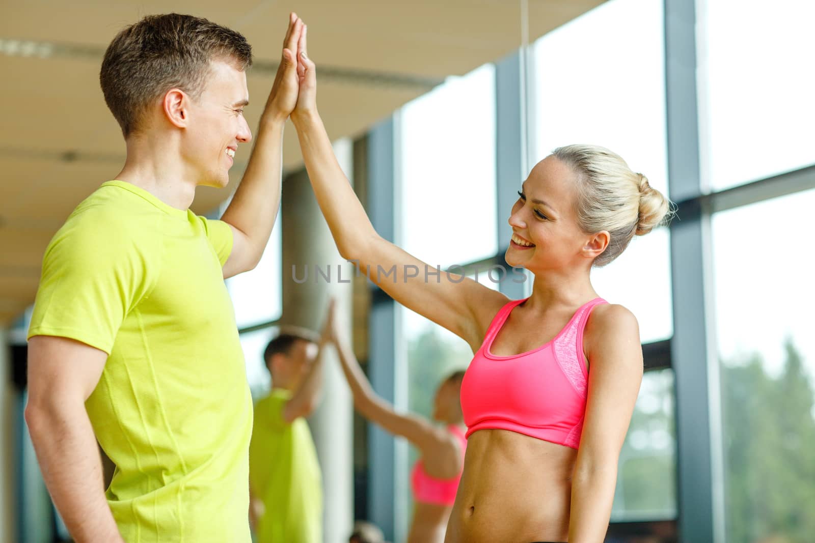 smiling man and woman making high five in gym by dolgachov