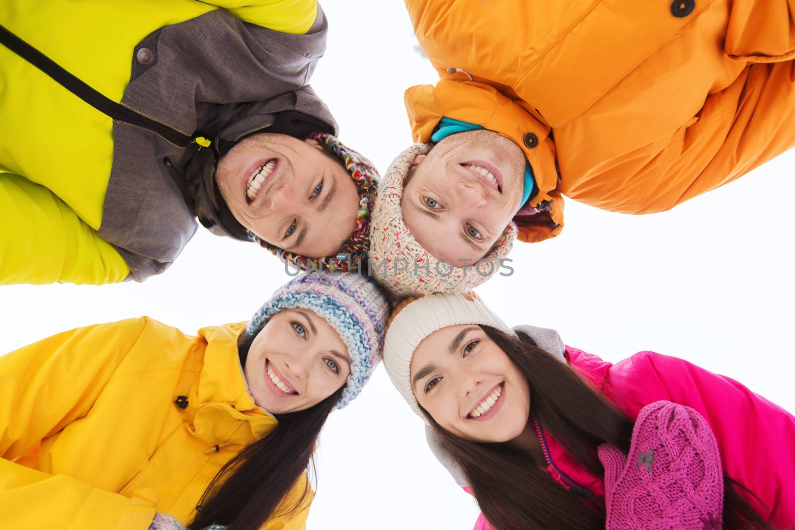 winter, leisure, friendship and people concept - happy friends standing in circle outdoors and looking down