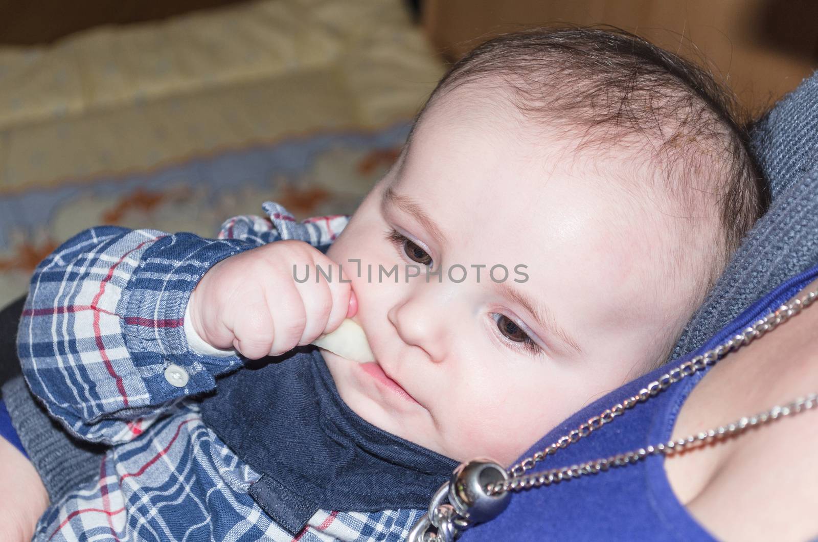 Portrait of a happy little boy.   Baby on the mother's arms. The toddler is eating.