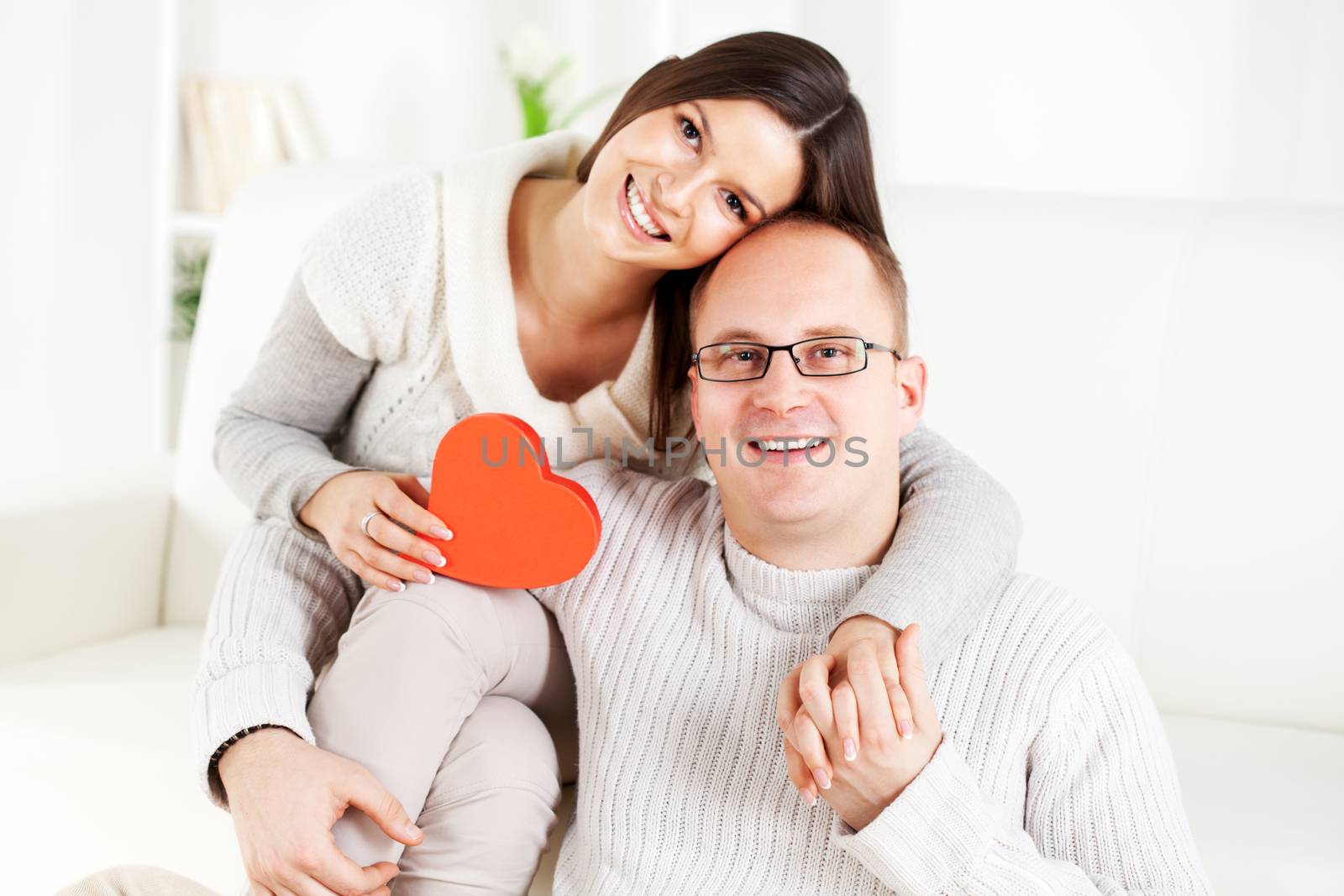 Happy beautiful Young couple in home interior with heart shaped box. Looking at camera. The valentine's day.