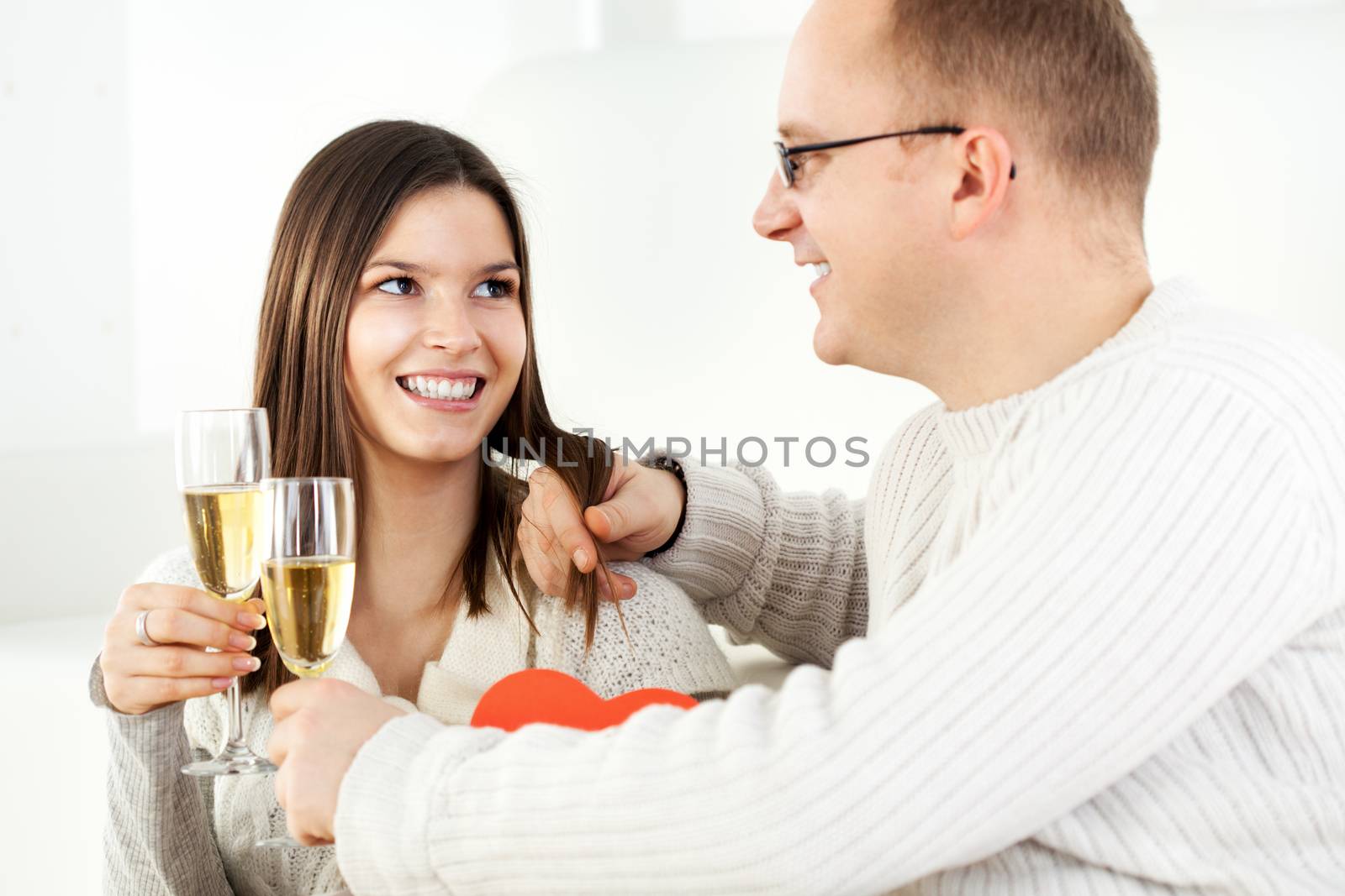 Happy Young couple in home interior enjoying in glass of champagne.