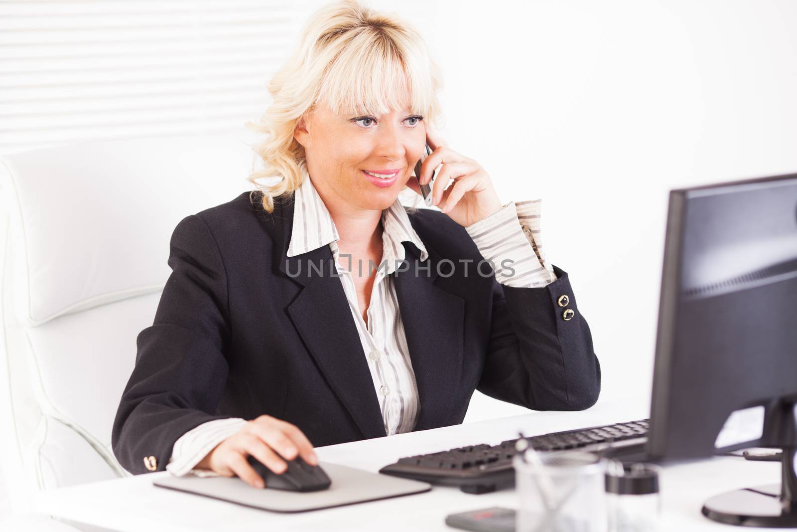 Beautiful mature Business woman talking on mobile phone at workplace.