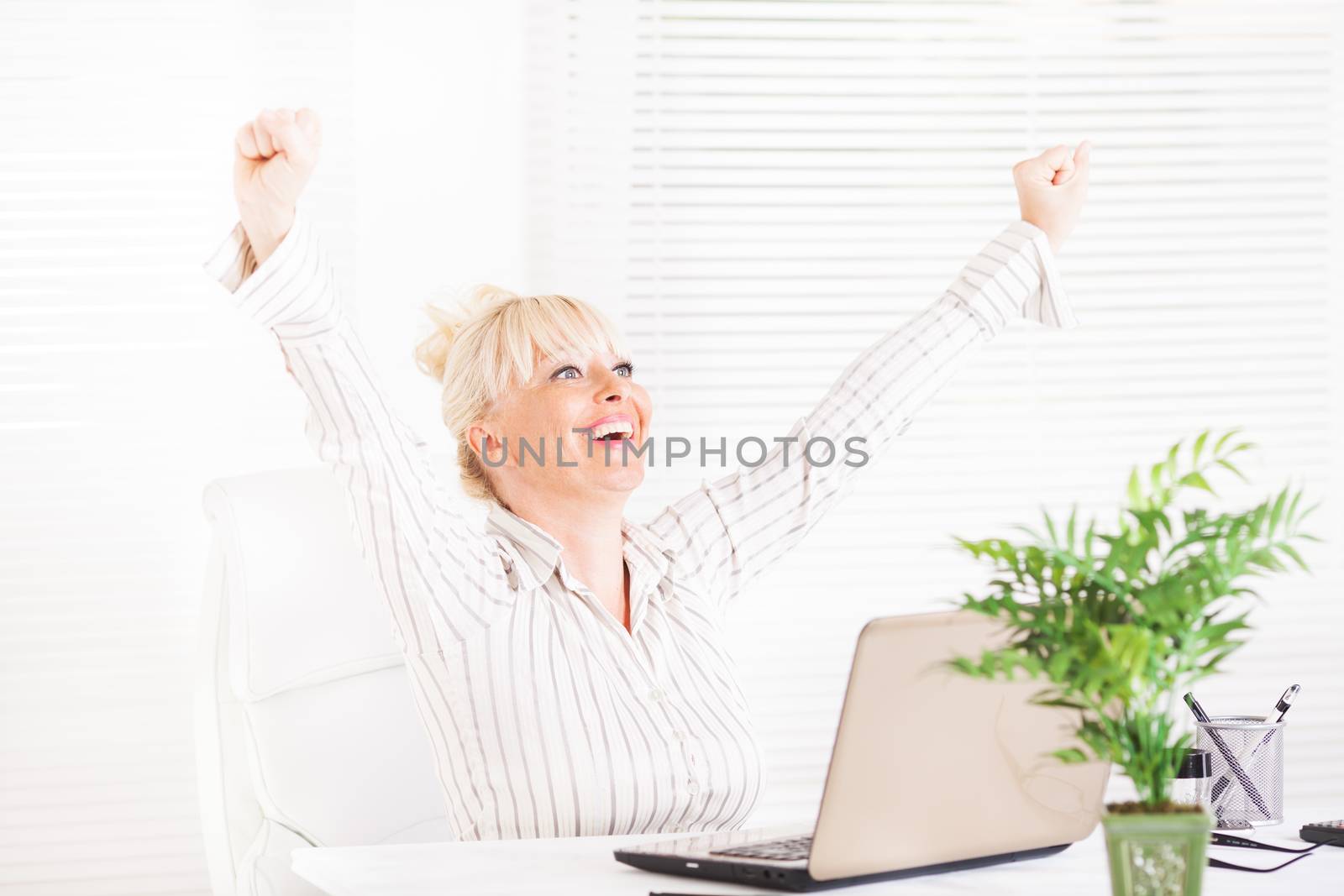 Cheerful Business woman sitting in the office with raising hands