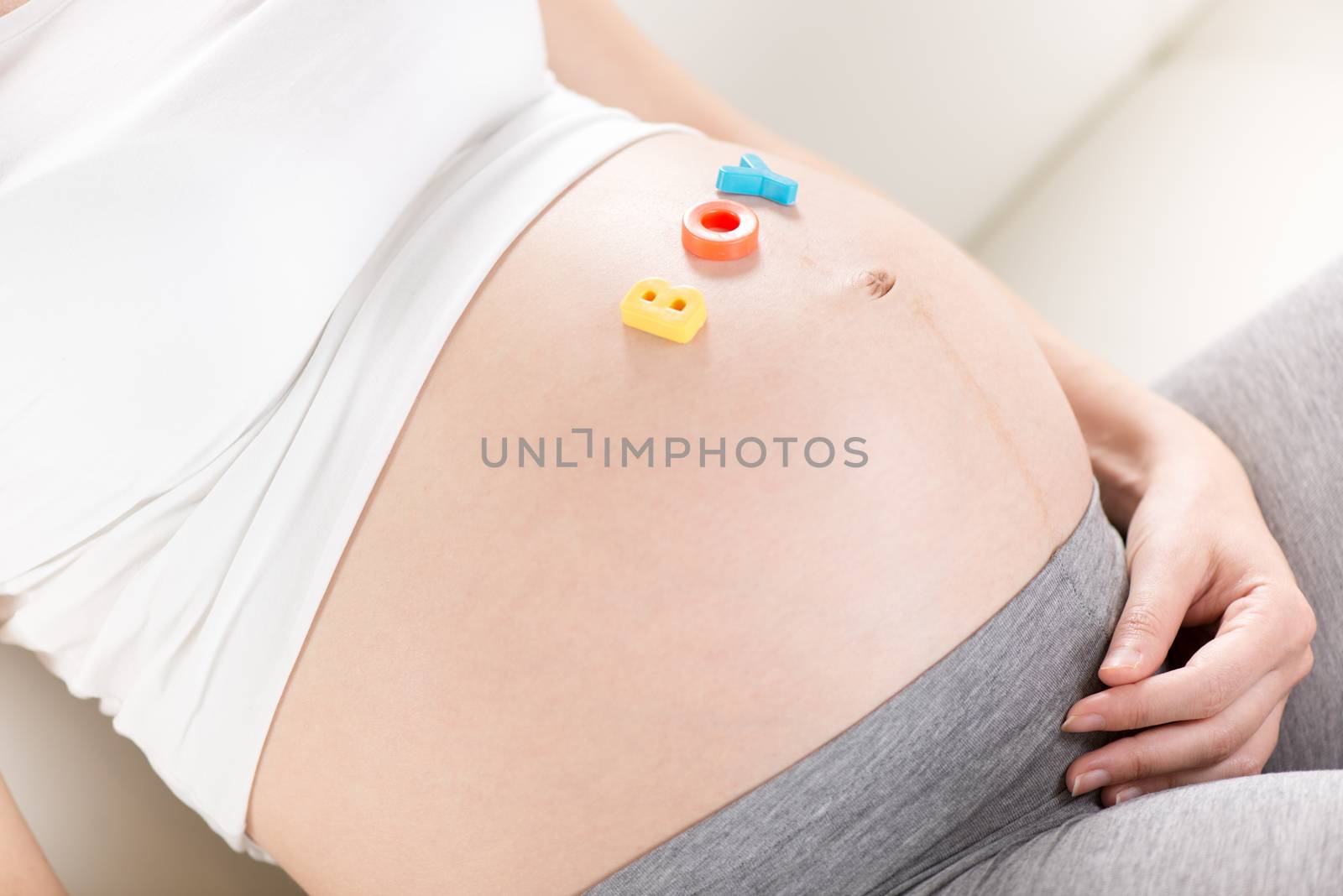 Multi Colored letters spelling Boy on a pregnant belly.