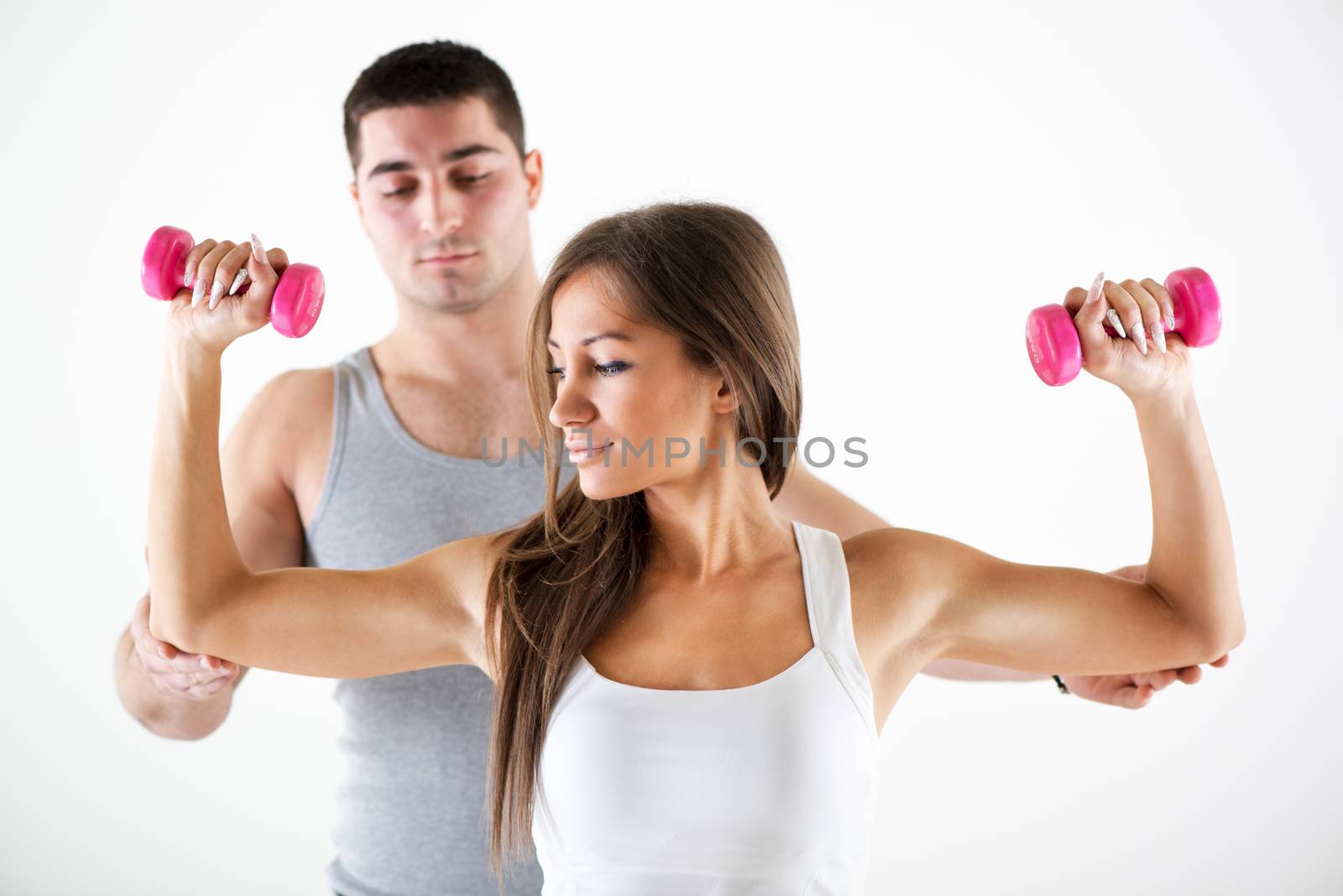 Young beautiful woman practicing upper body muscle group with personal trainer.