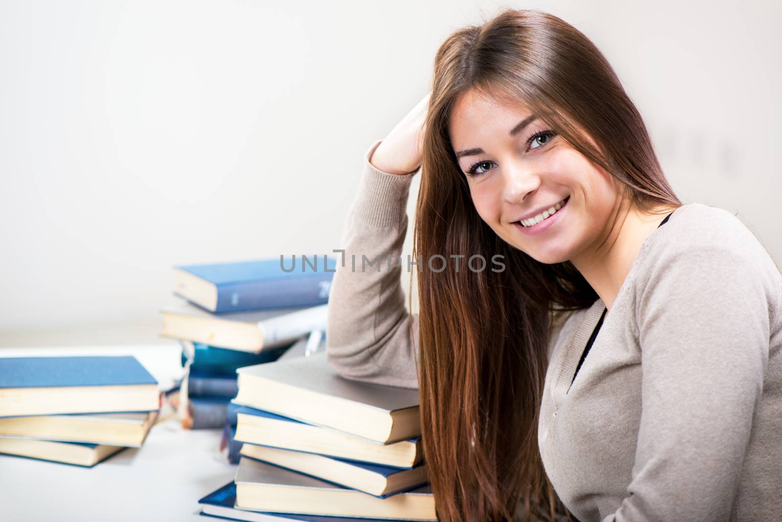 Portrait of Cute Young woman with many books. Looking at camera.