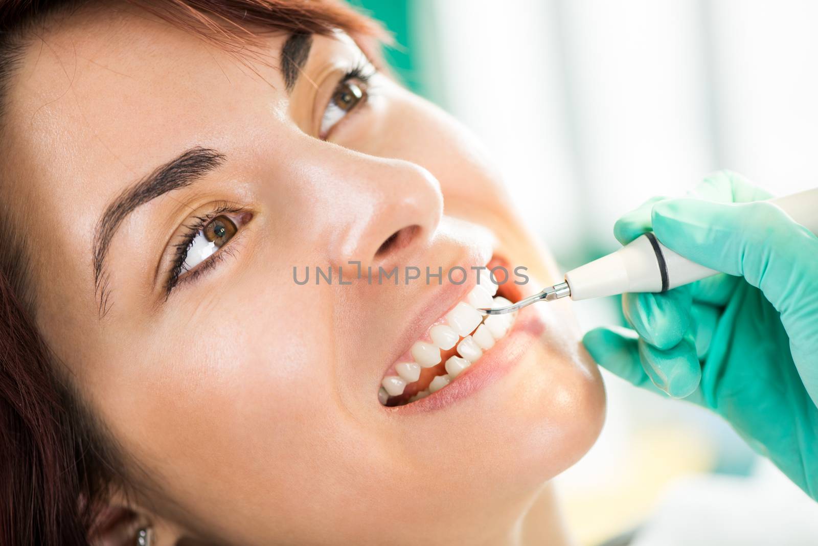 Dentist examination and cleaning patient teeth in the office with metal dental pick tool.