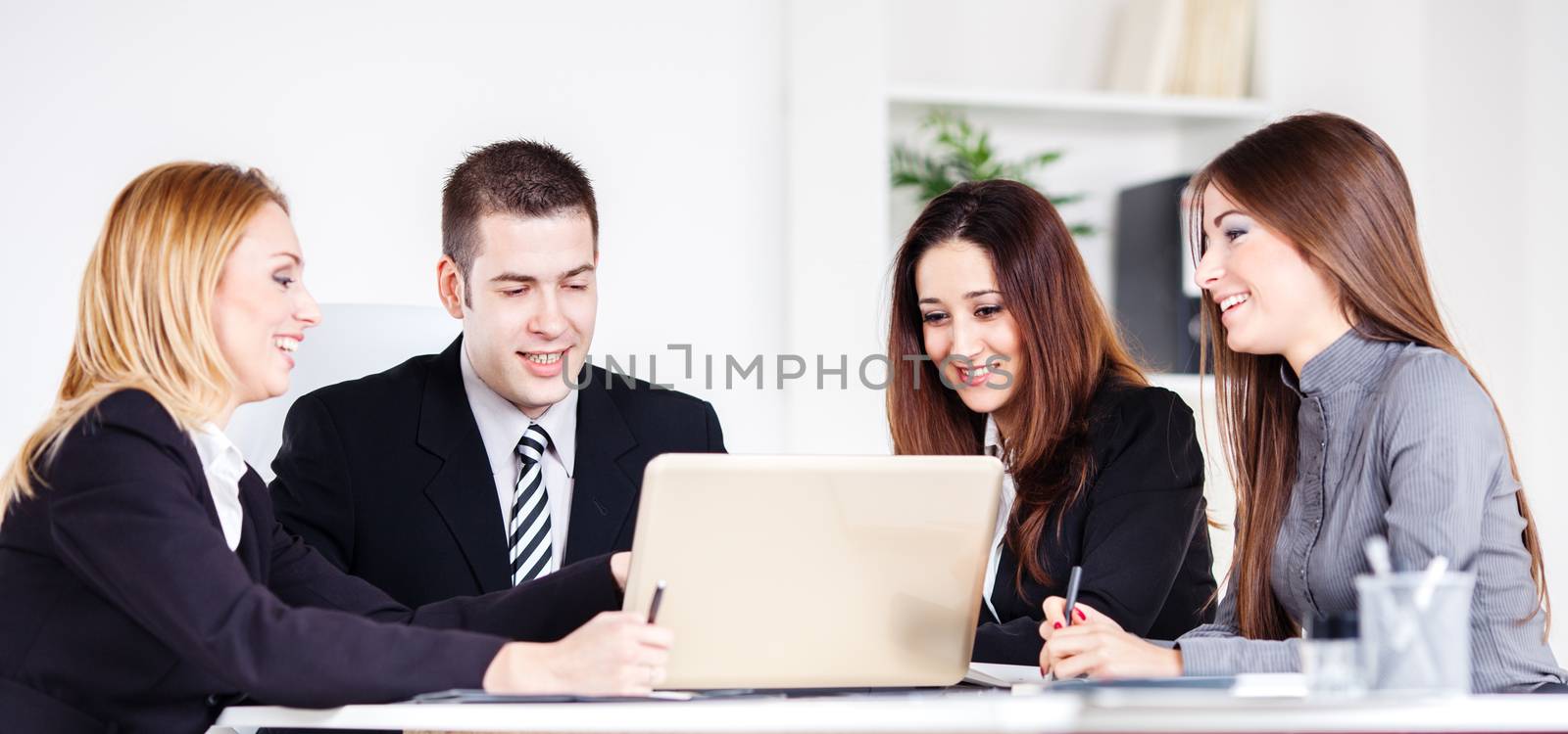 Four happy Business people looking project at laptop in the office.