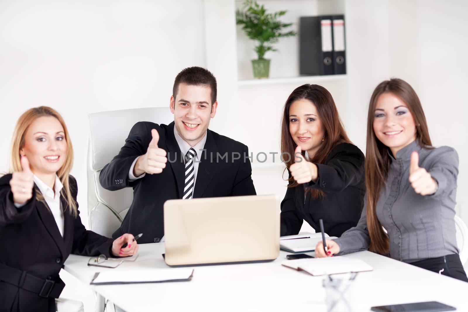 Four happy Business people showing thumbs up in the office, Looking at camera.