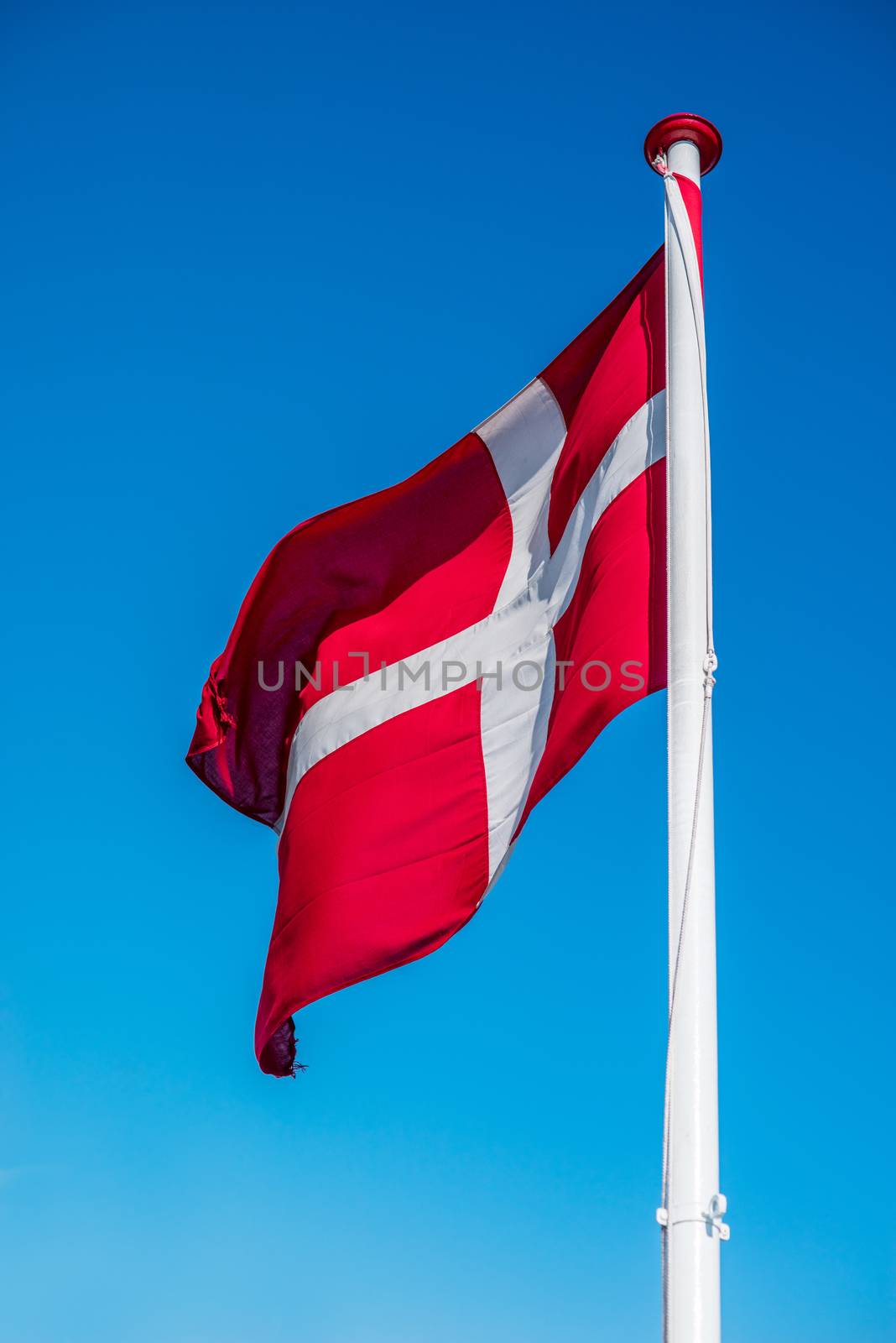Denmark flag on a pole in blue sky