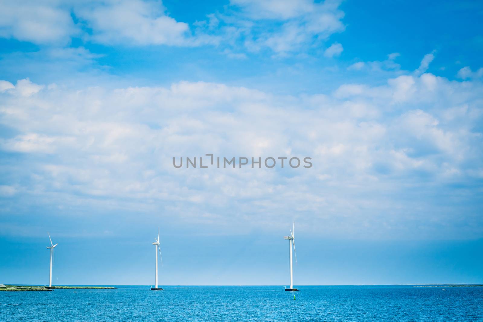 Windmills on a row in the blue ocean