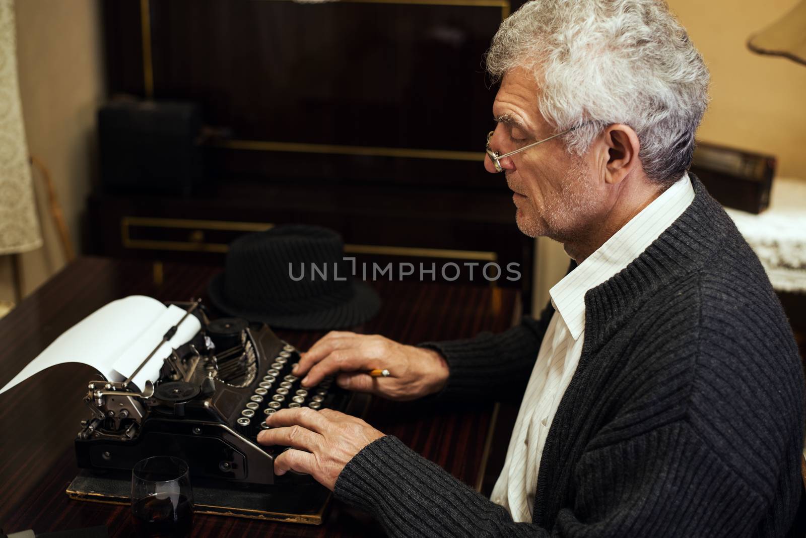 Retro Senior man writer with glasses writing on Obsolete Typewriter.