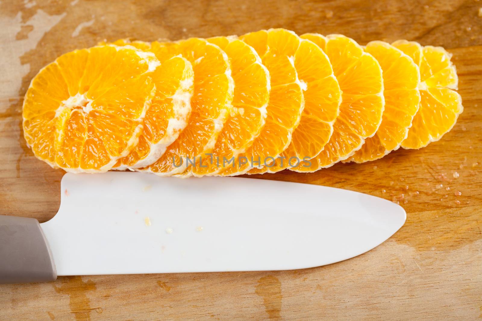 Sliced ​​orange on kitchen board with kitchen knife next. Close-up.