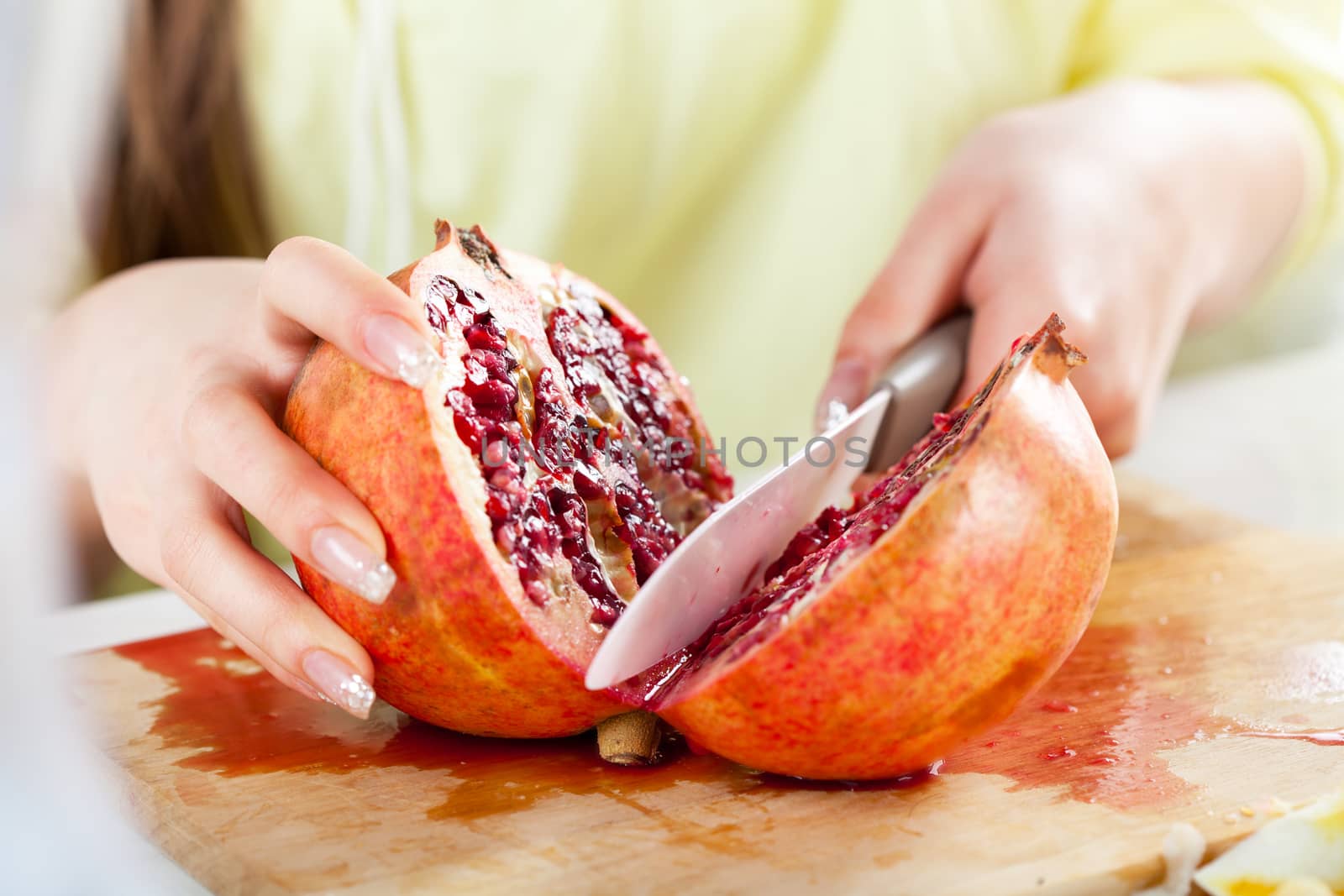 Female hands Cutting pomegranate in a kitchen. Close-up.