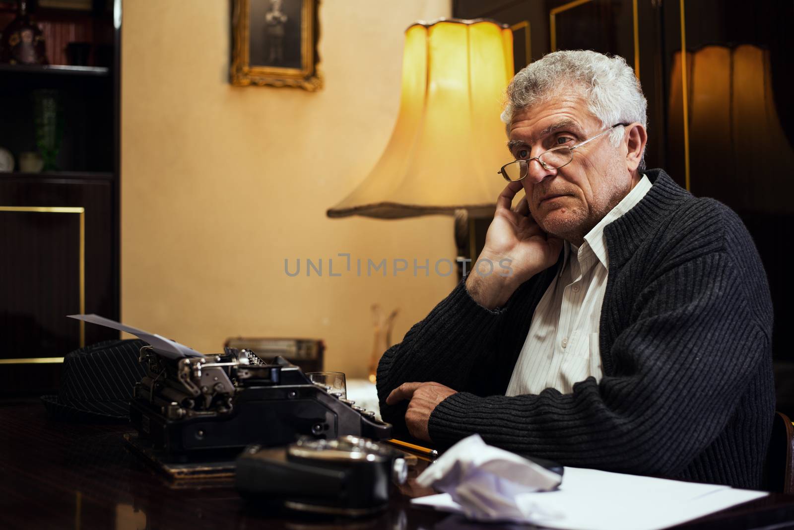 Retro Senior Man writer with Glasses sitting at the Desk and thinking.