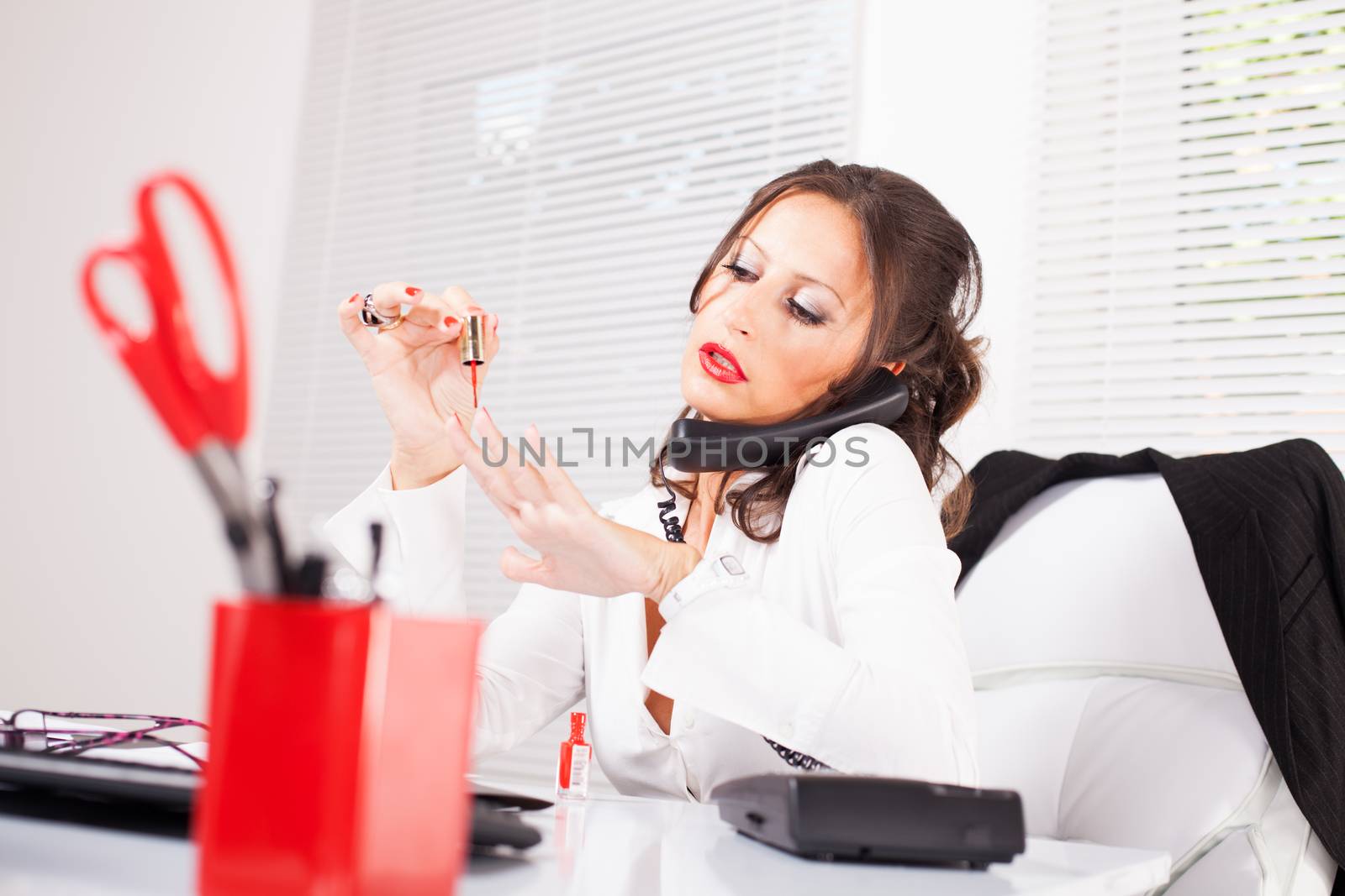 Attractive sexy secretary lacquered nails  in the office and talking on the phone