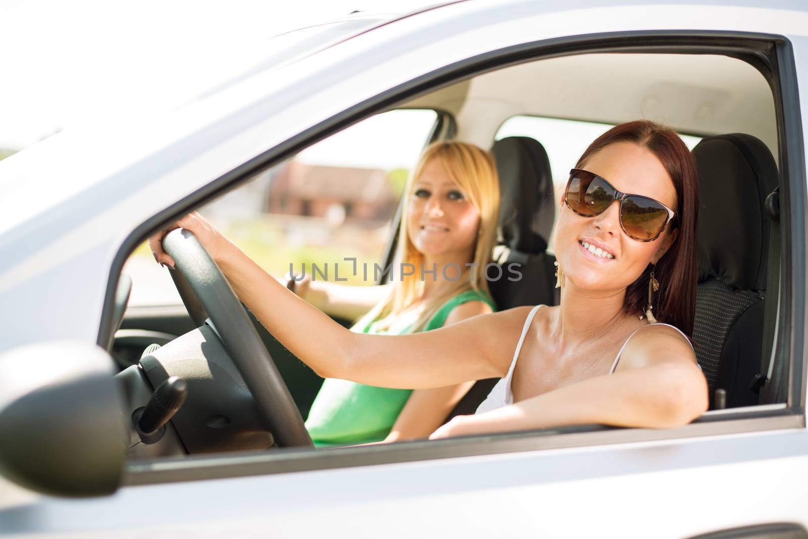 Young female friends sitting in car, and ready for vacation.