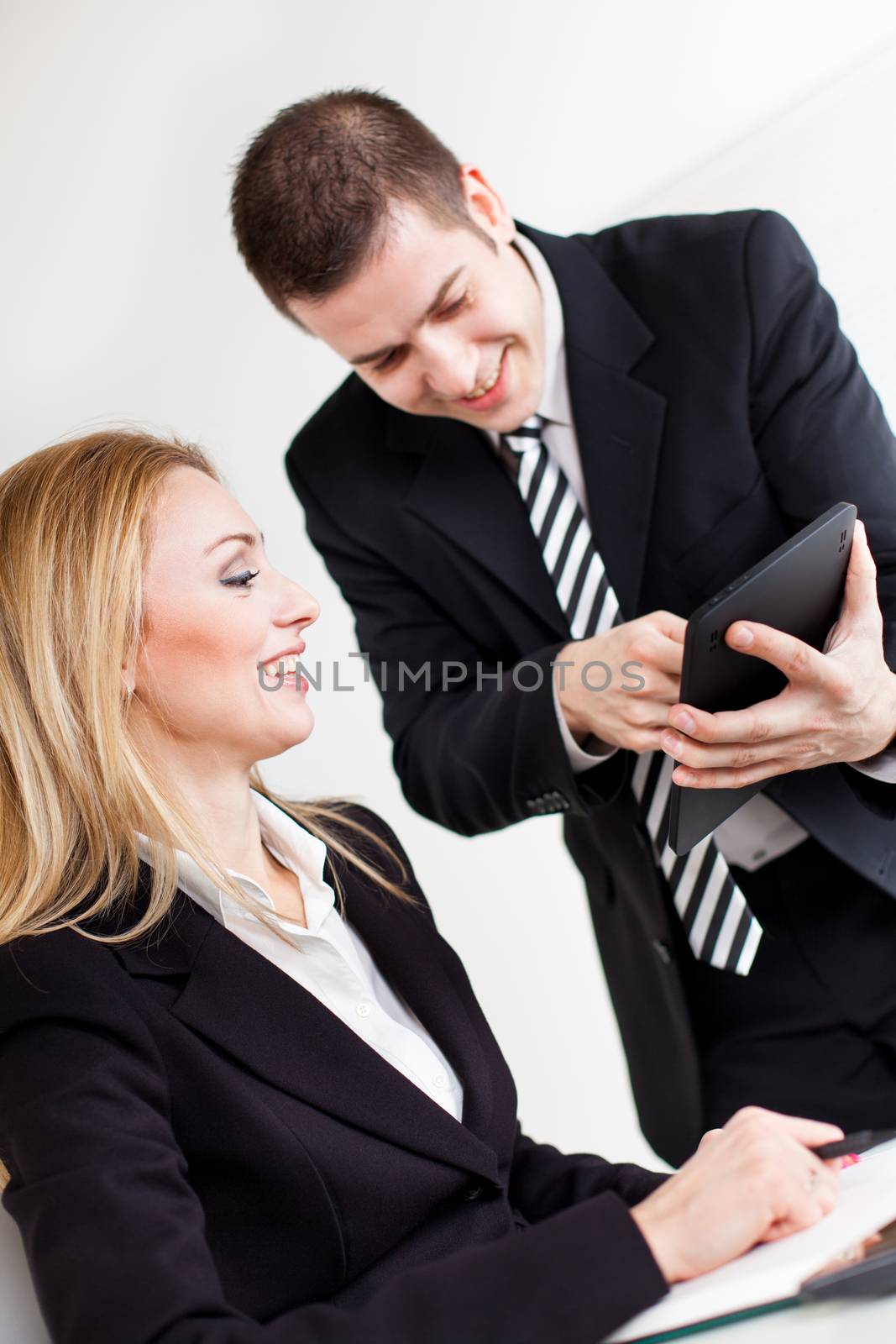 Happy Businessman showing her businesswoman colleague project at Digital Tablet.
