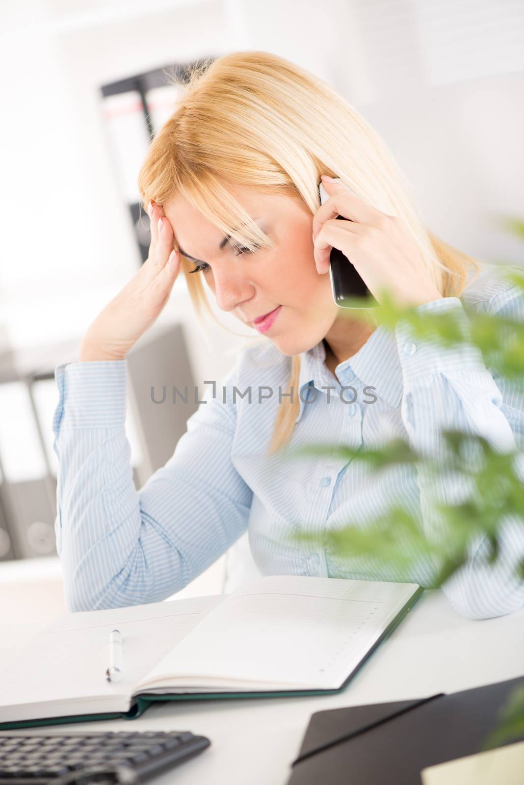 Worried Businesswoman telephoning and thinking in the office.