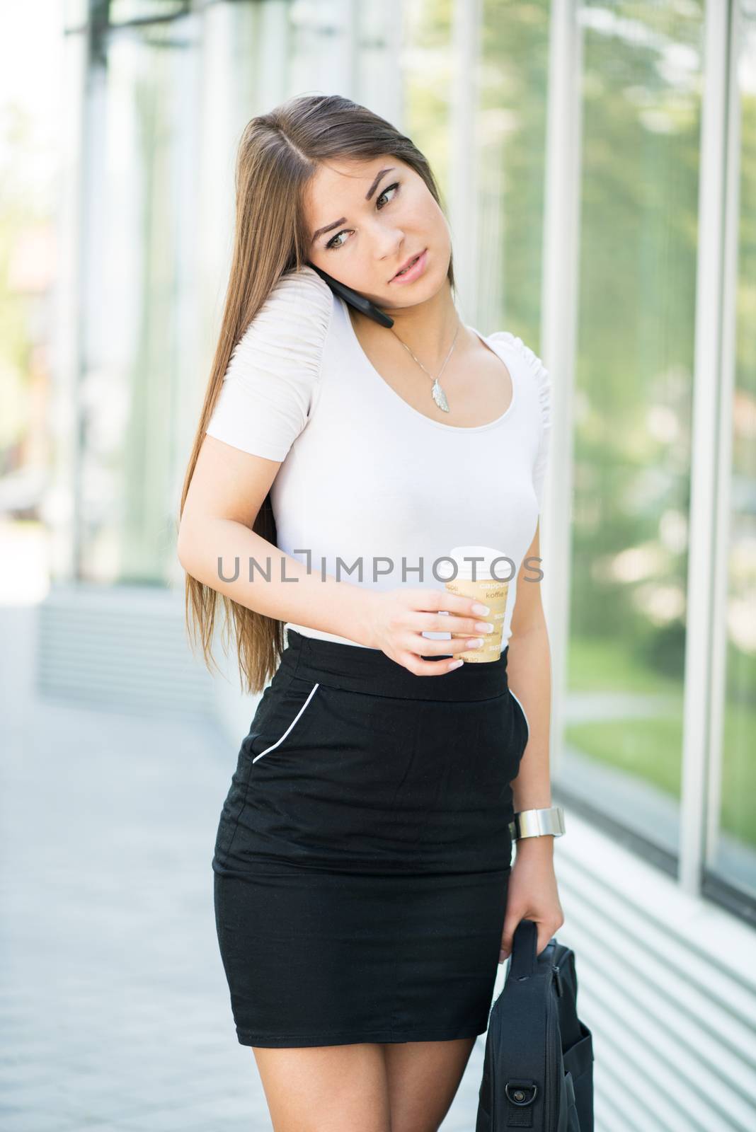 Overworked Businesswoman walking on the street and using a Cell Phone.