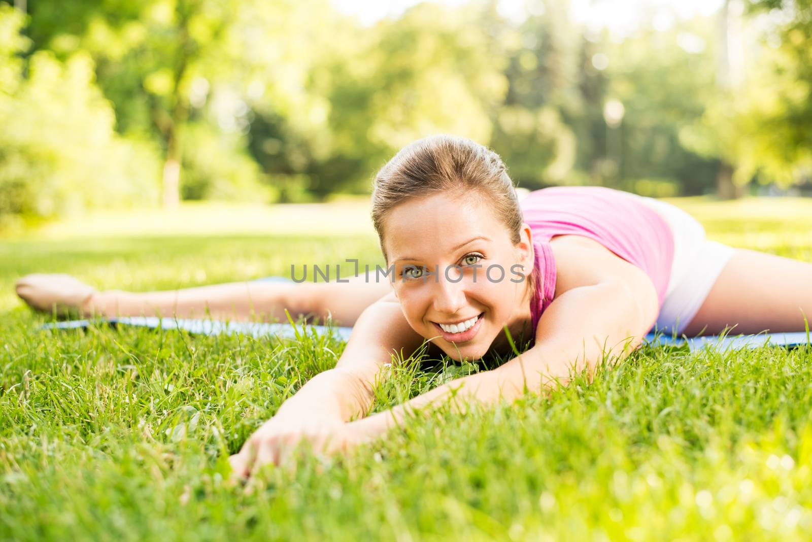 Cute young woman doing stretching exercises in the park. Close Up.