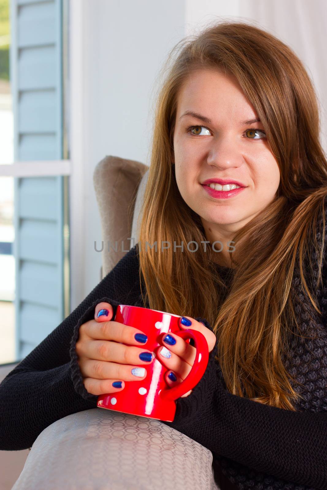 beautiful woman drinking coffee in the morning sitting by the window