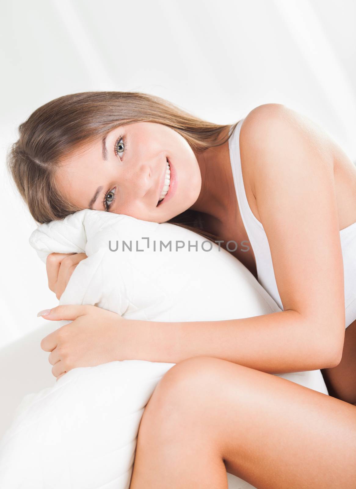 Beautiful cute girl lying in underwear and hugging pillow.