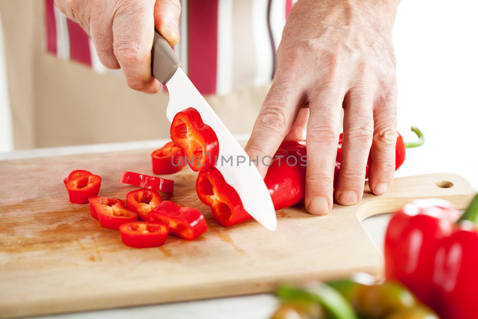Senior Male Hands Cutting red peppers on the kitchen board