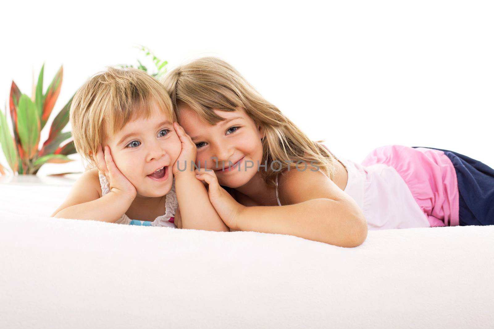 Two Happy little girls lying on bed and hugging each other