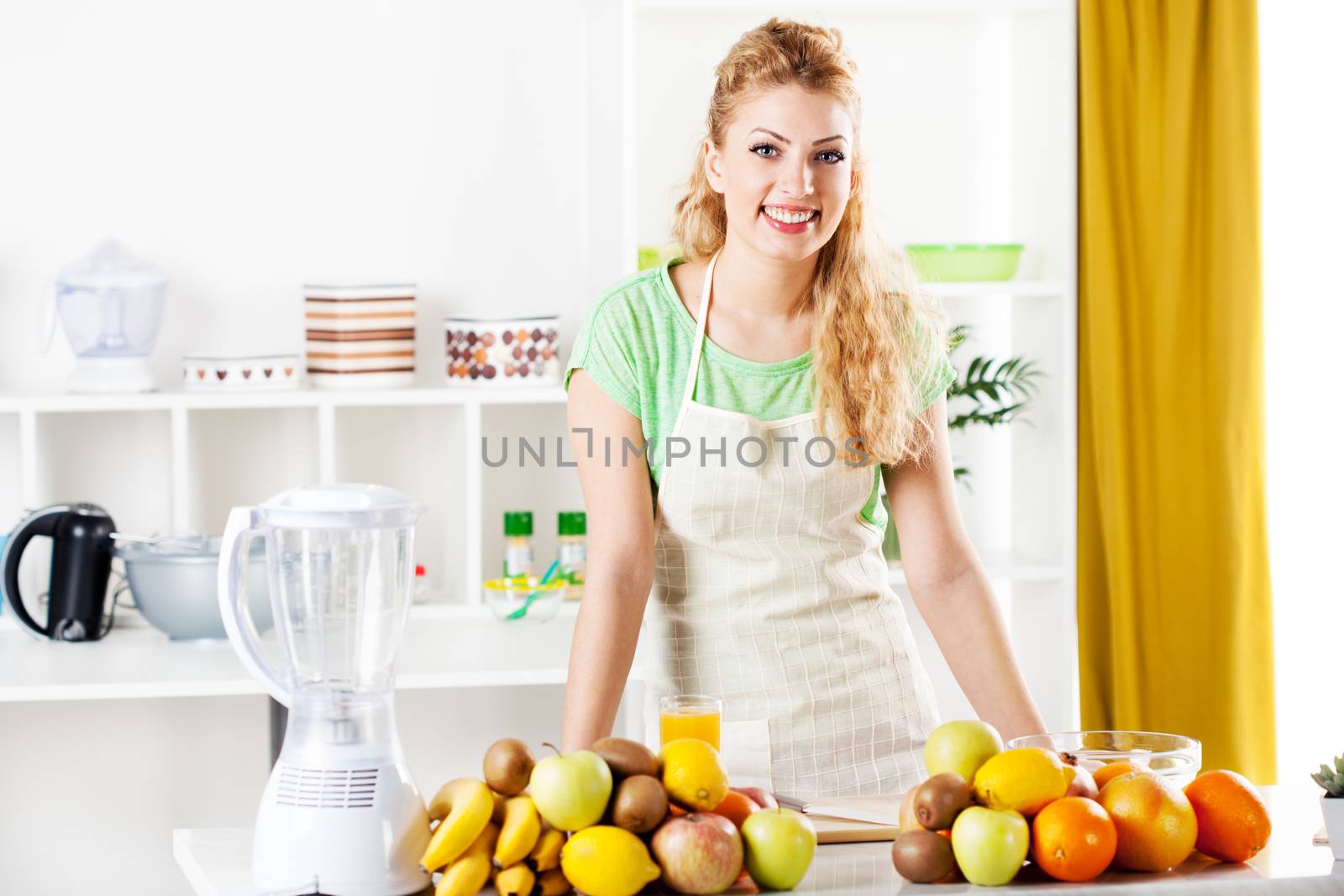 Beautiful young woman in a kitchen with fruits. Looking at camera.