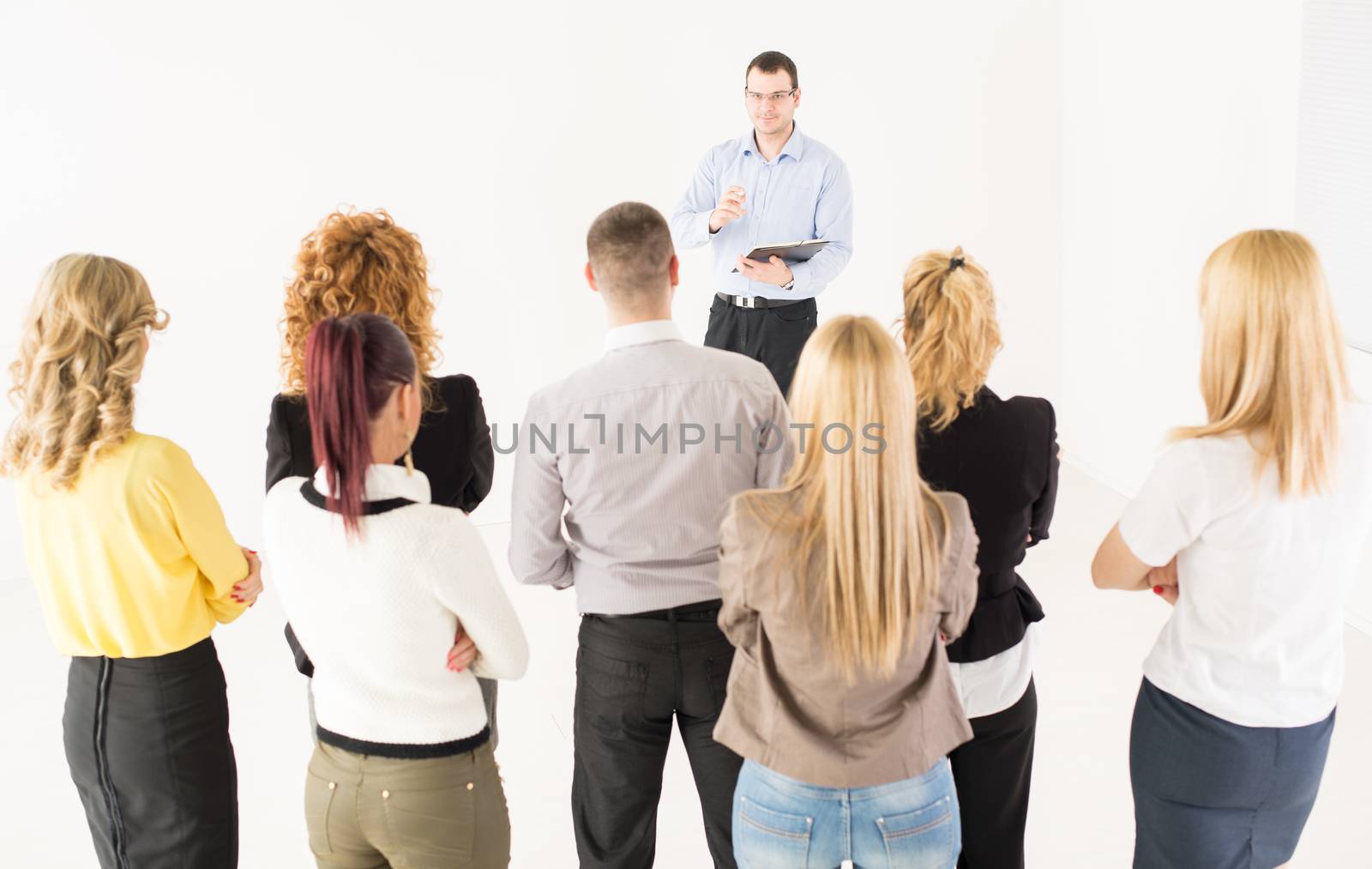 Friendly business man explaining plan of work in front of coworkers. The team is listening.