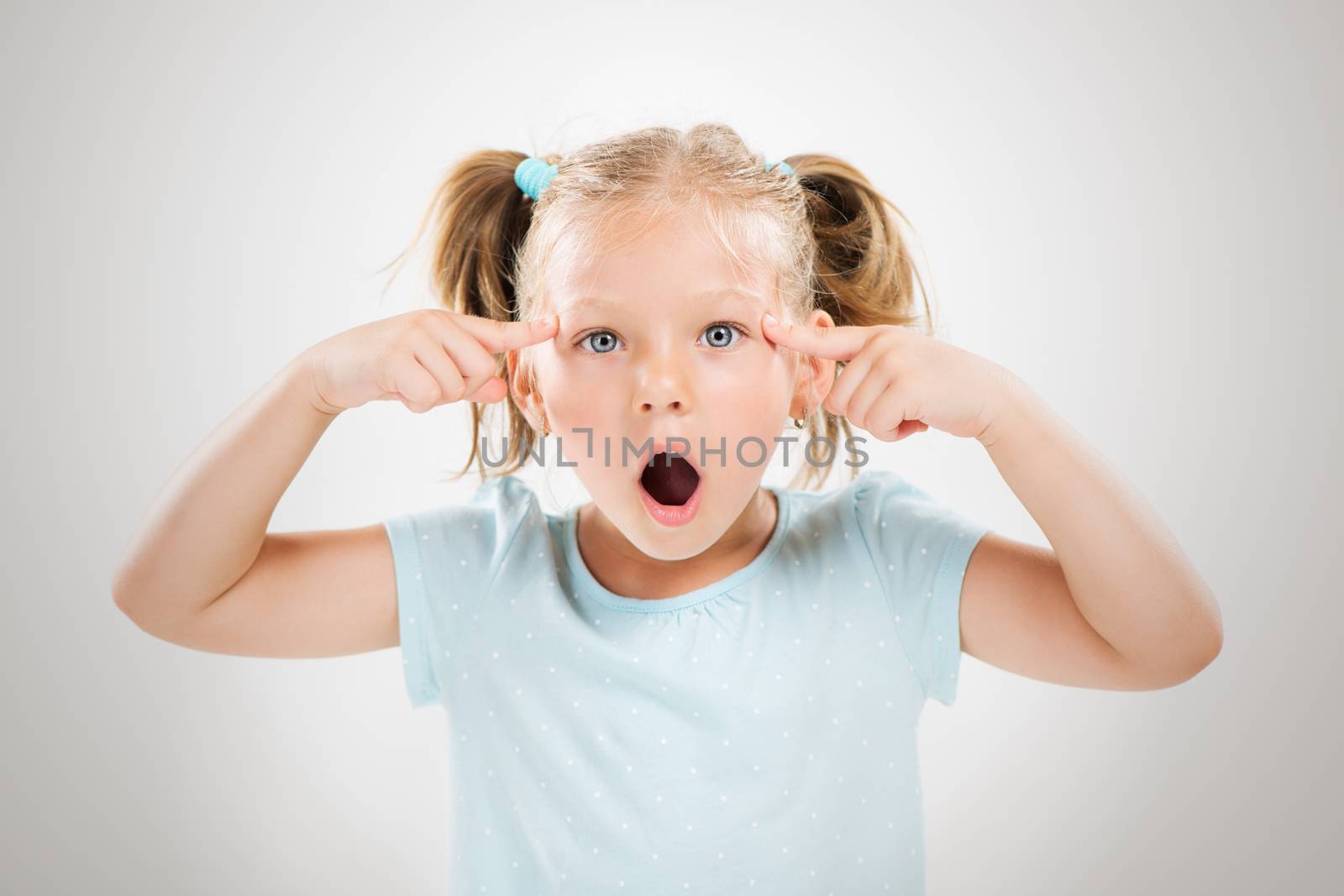 Cute little girl giving a sign with fingers on her head. She says, are you crazy?