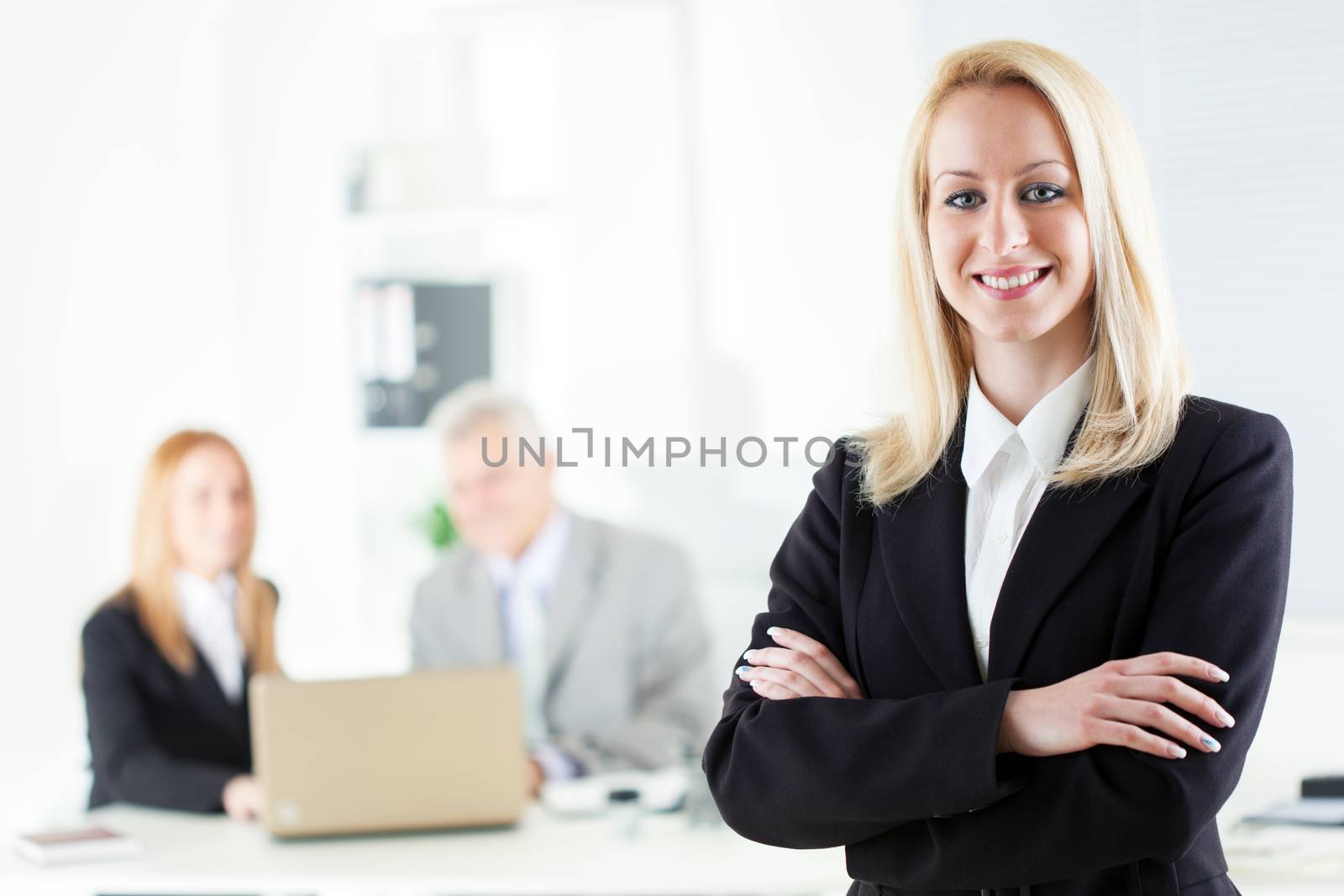 Beautiful young businesswoman with Arms Crossed in the office. Looking at camera. Selective Focus.