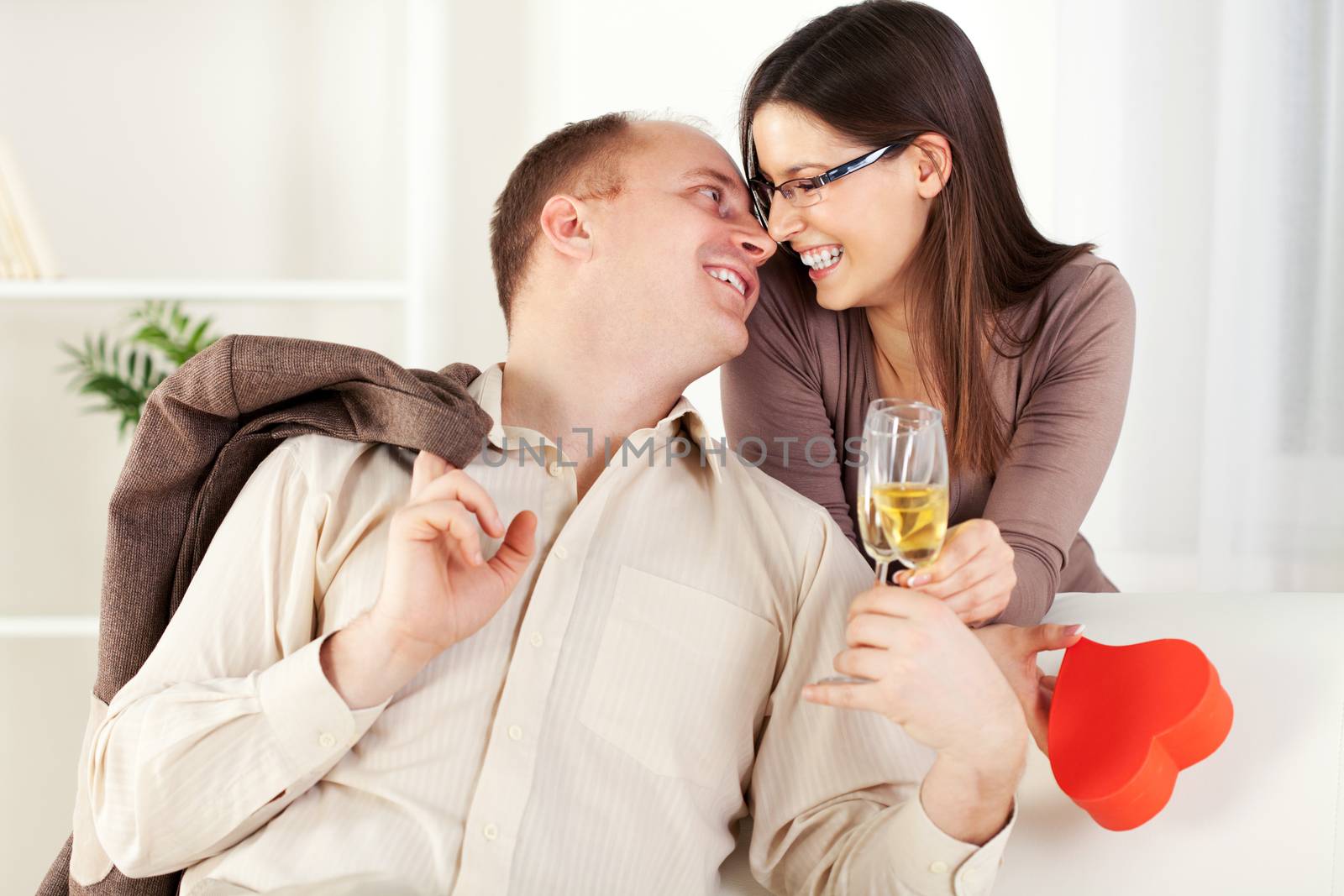 Happy Young couple in home interior enjoying in glass of champagne and touching noses. The valentine's day.
